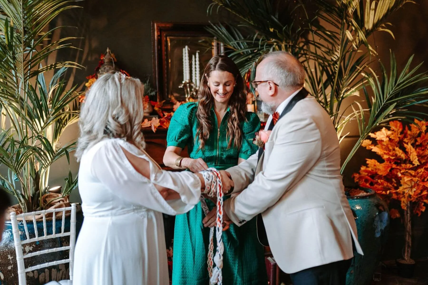 At Lost and Found Club in Leeds, Michelle Park Celebrant, draps handfatsing cords over the wrists of a bride and groom, a part of a handfasting ceremony.