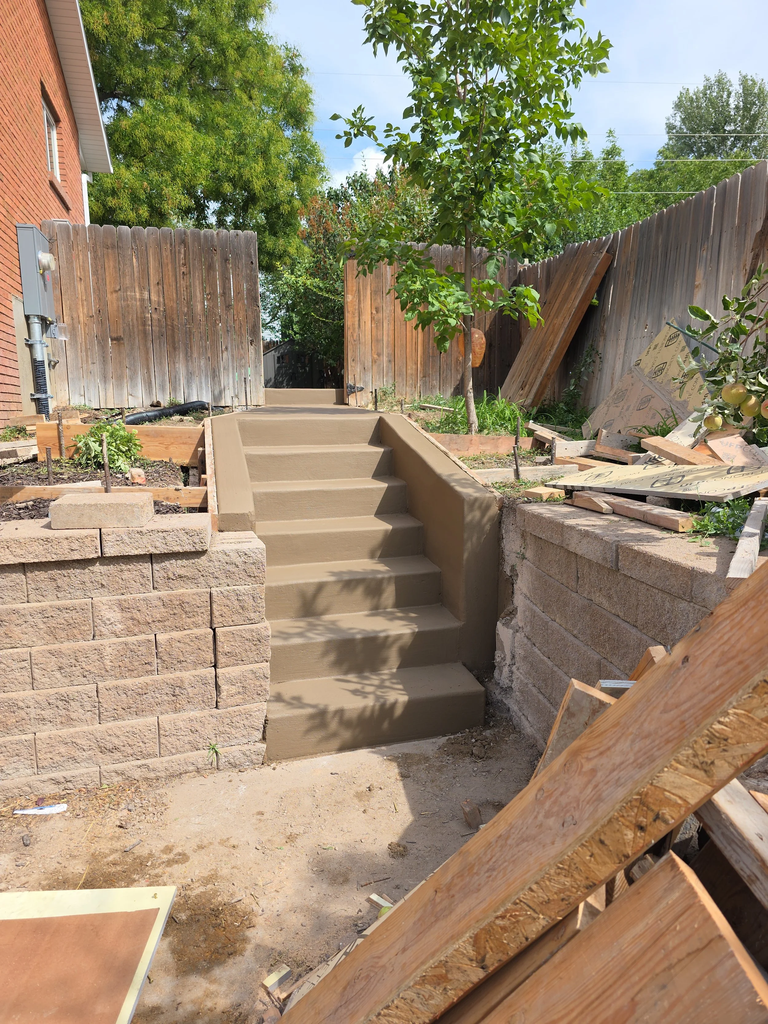 Custom colored concrete steps, retaining wall, RV pad, and patio installation at a residential home in Spanish Fork, Utah.