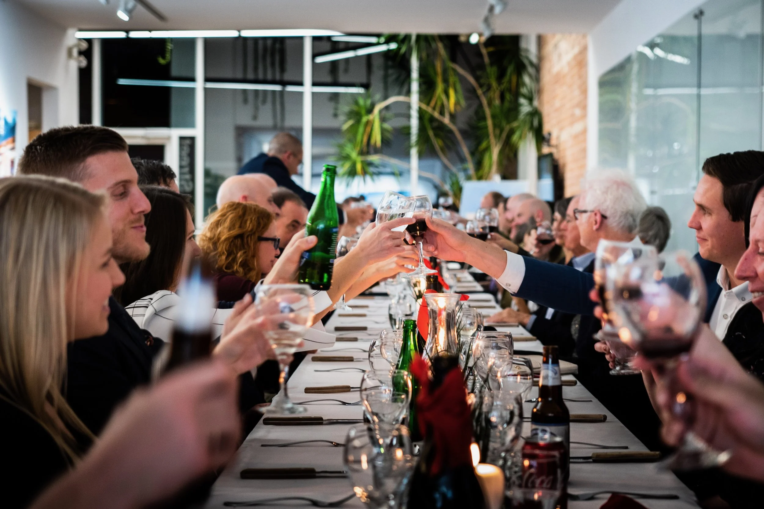The Lett team sits across from one another at a long narrow table, clinking wine glasses together in the middle in celebration.