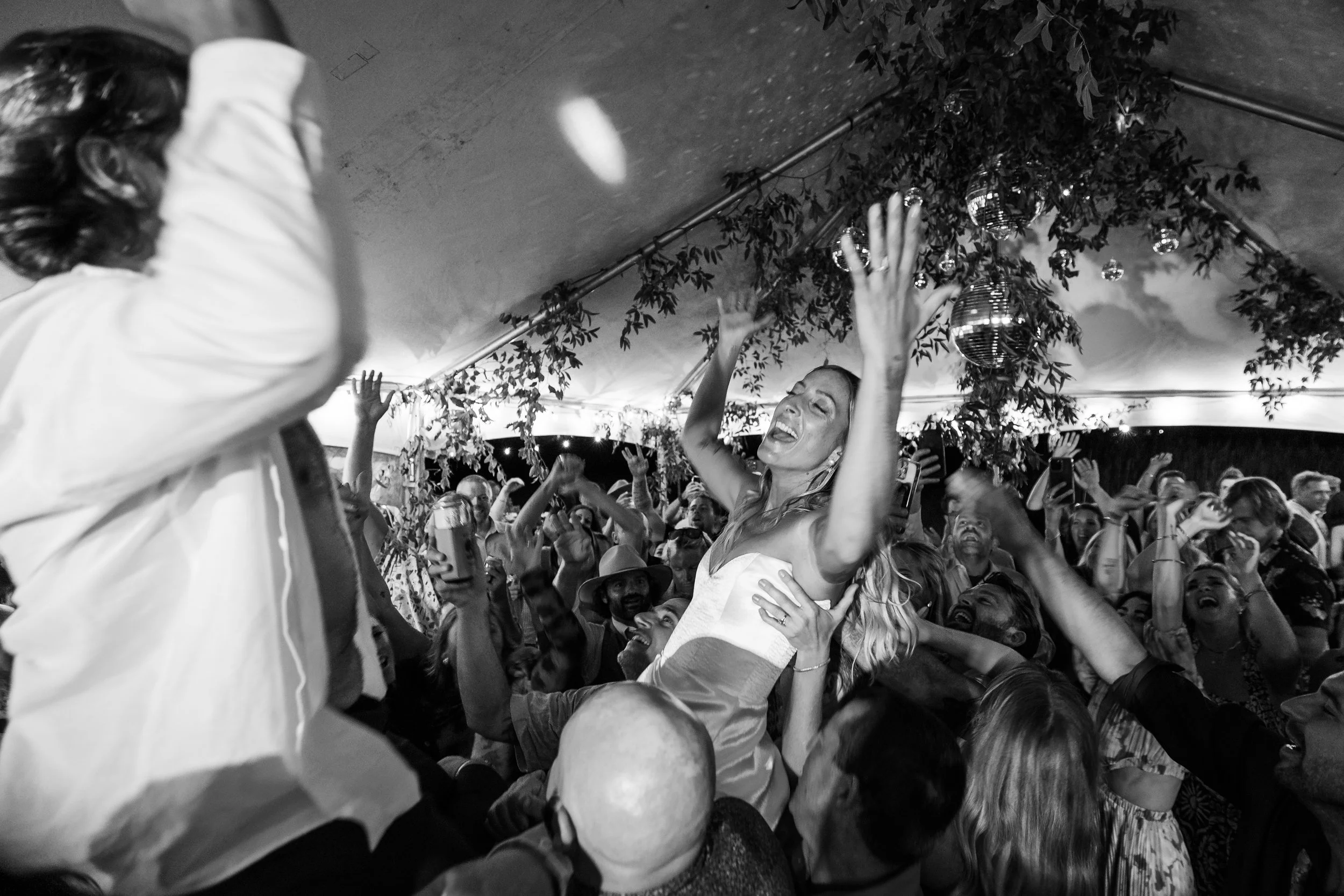 People dancing and celebrating at a lively event under a decorated tent.