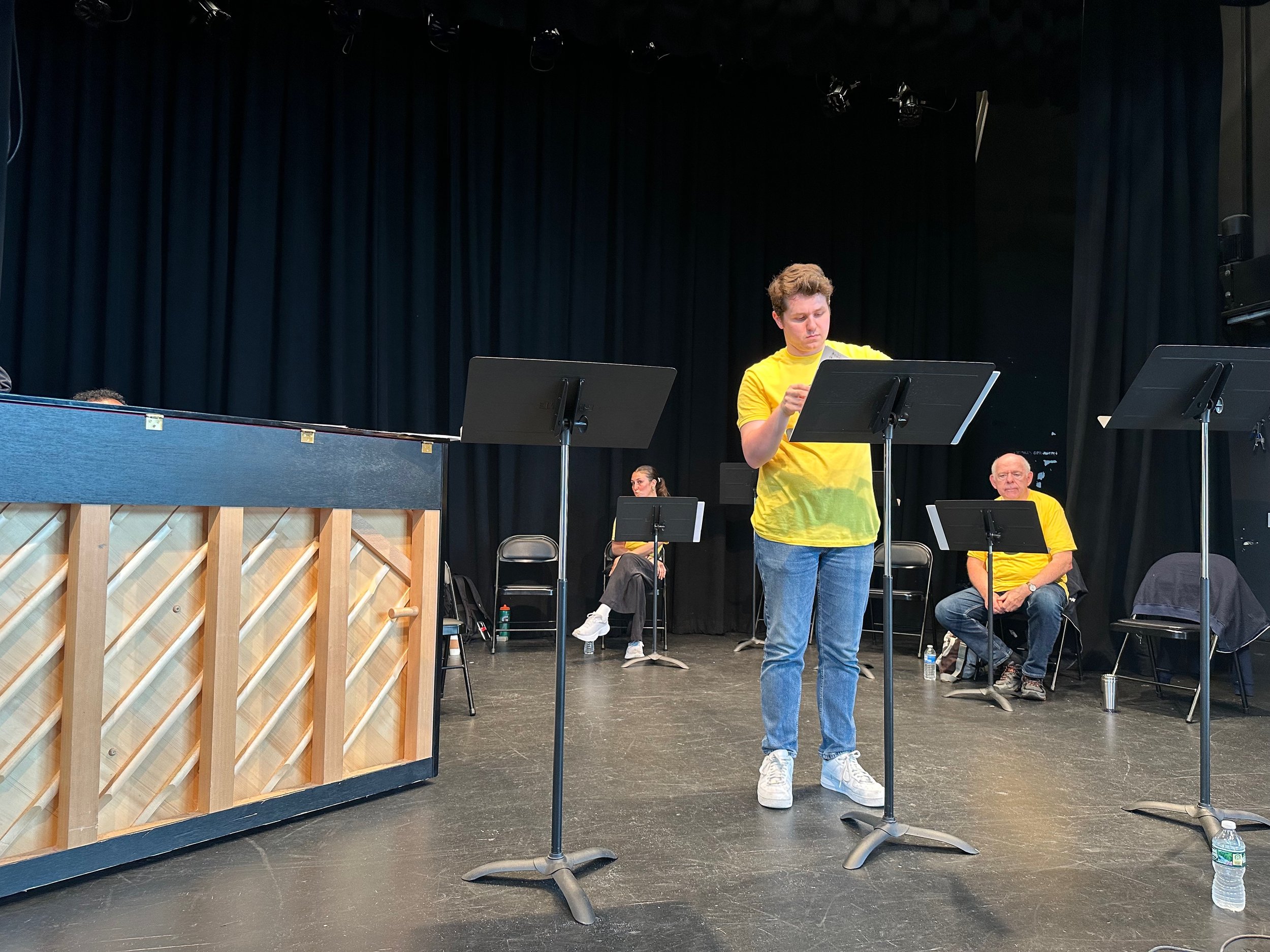 Actor In Yellow T-Shirt Rehearsing With Music Stand On Stage