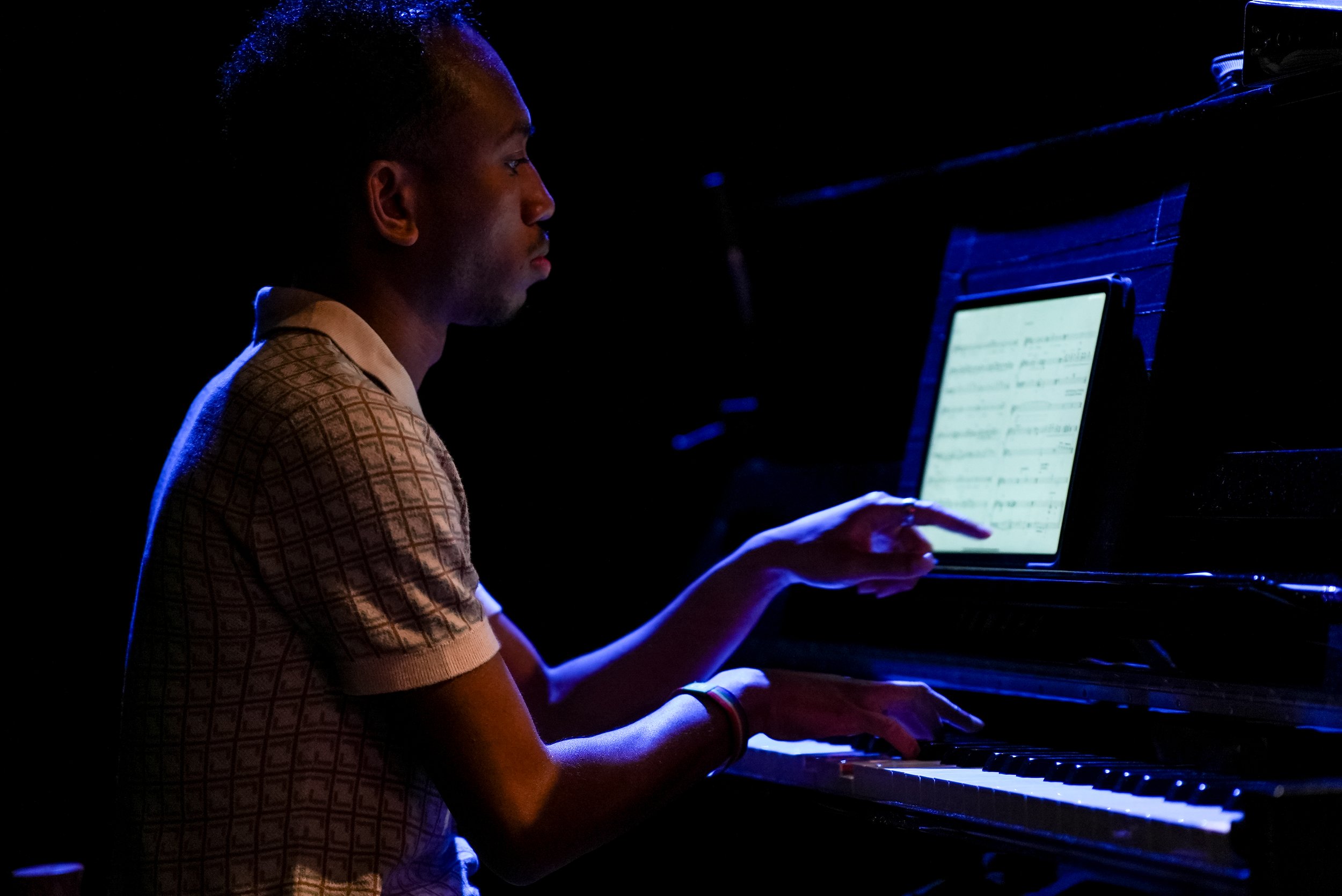 Pianist at a black piano with ipad showing music notes