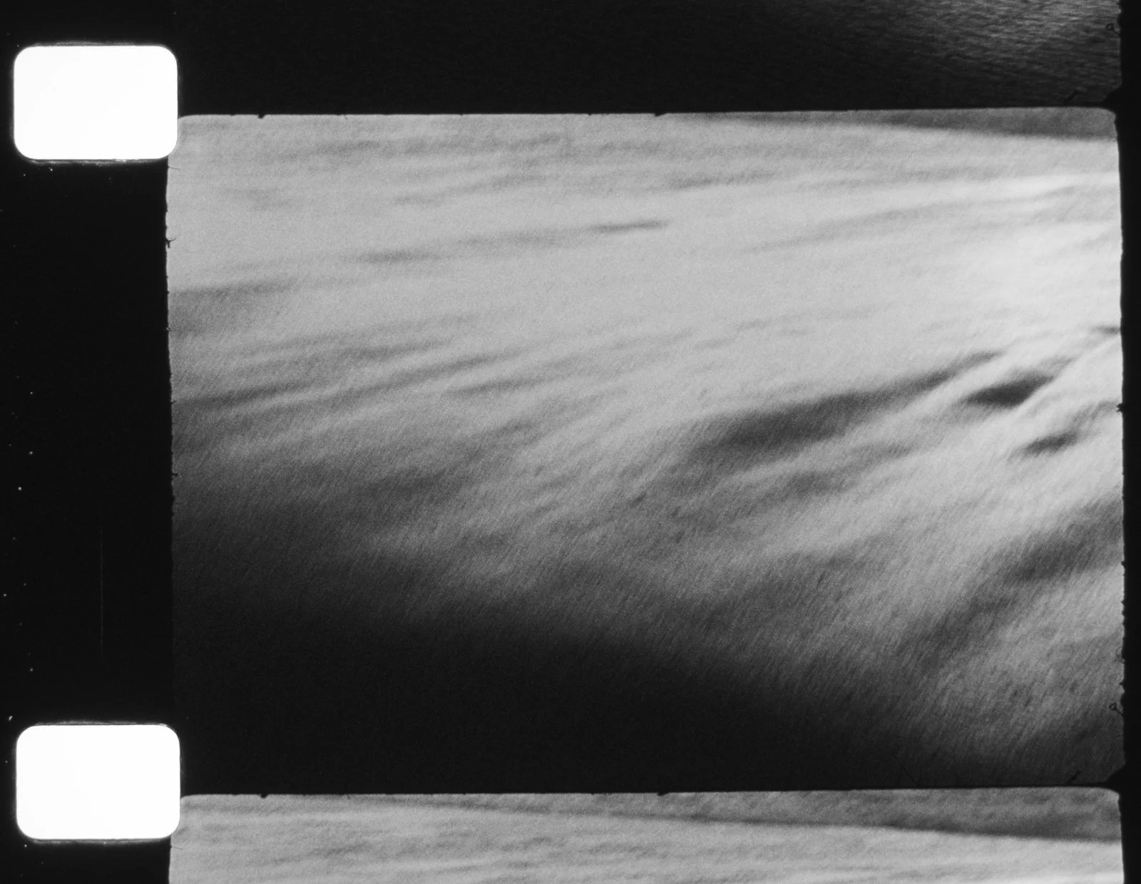Black and white photograph of a large body of water with gentle ripples, taken from a high angle.