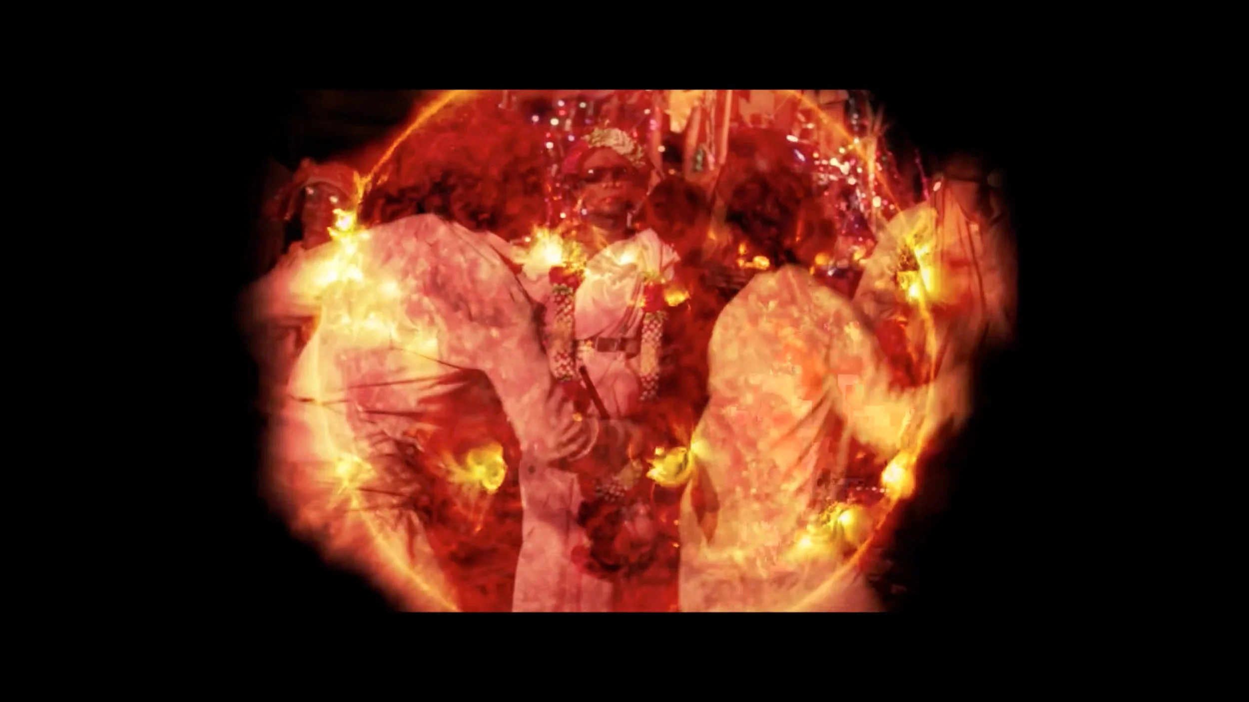 Hindu priests performing a religious ceremony, surrounded by fire and bright lights, with traditional attire and decorations.