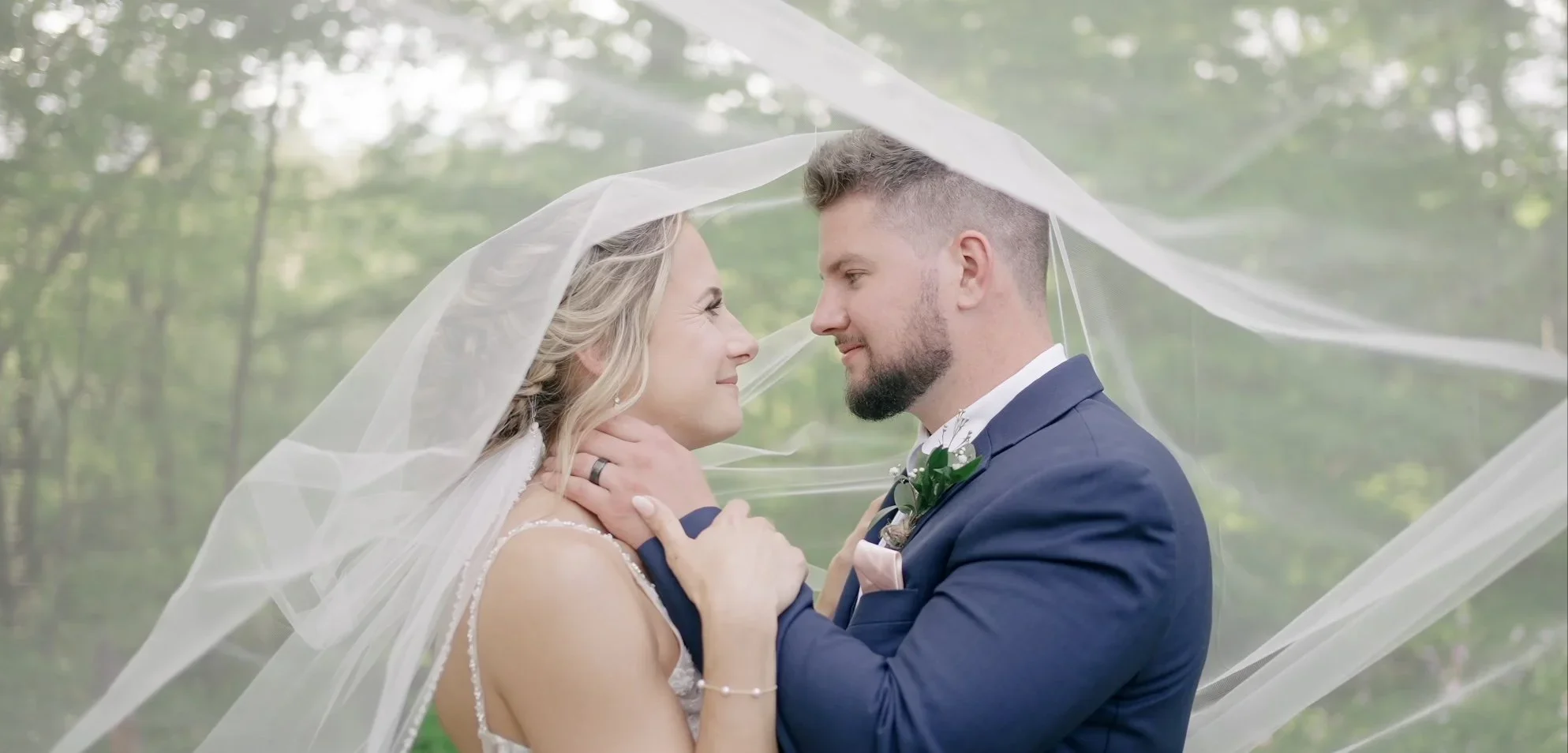 bride and groom looking into each other's eyes with wind blowing through her veil