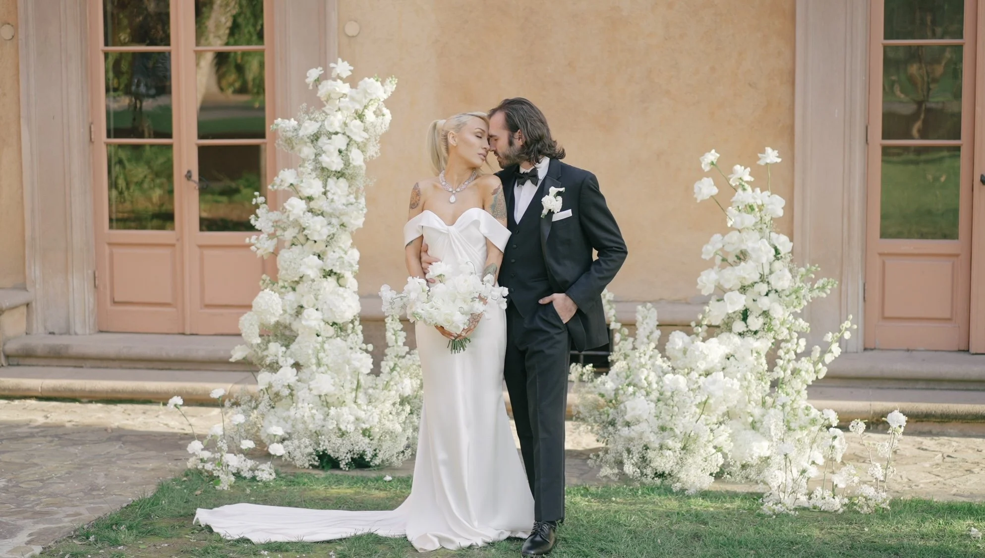 couple on their wedding day standing next to white floral installations