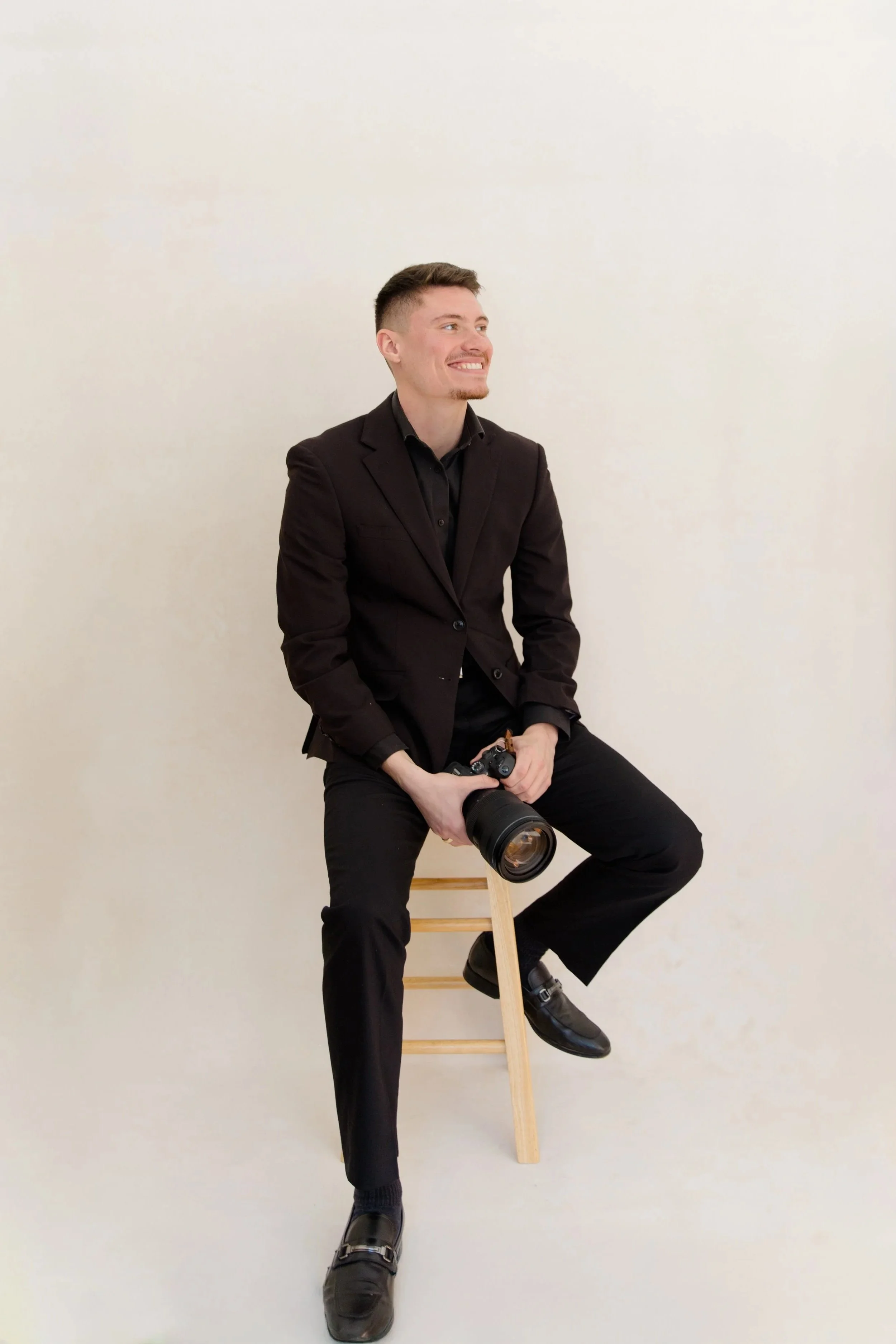 Adam Gorham sitting on a stool with camera