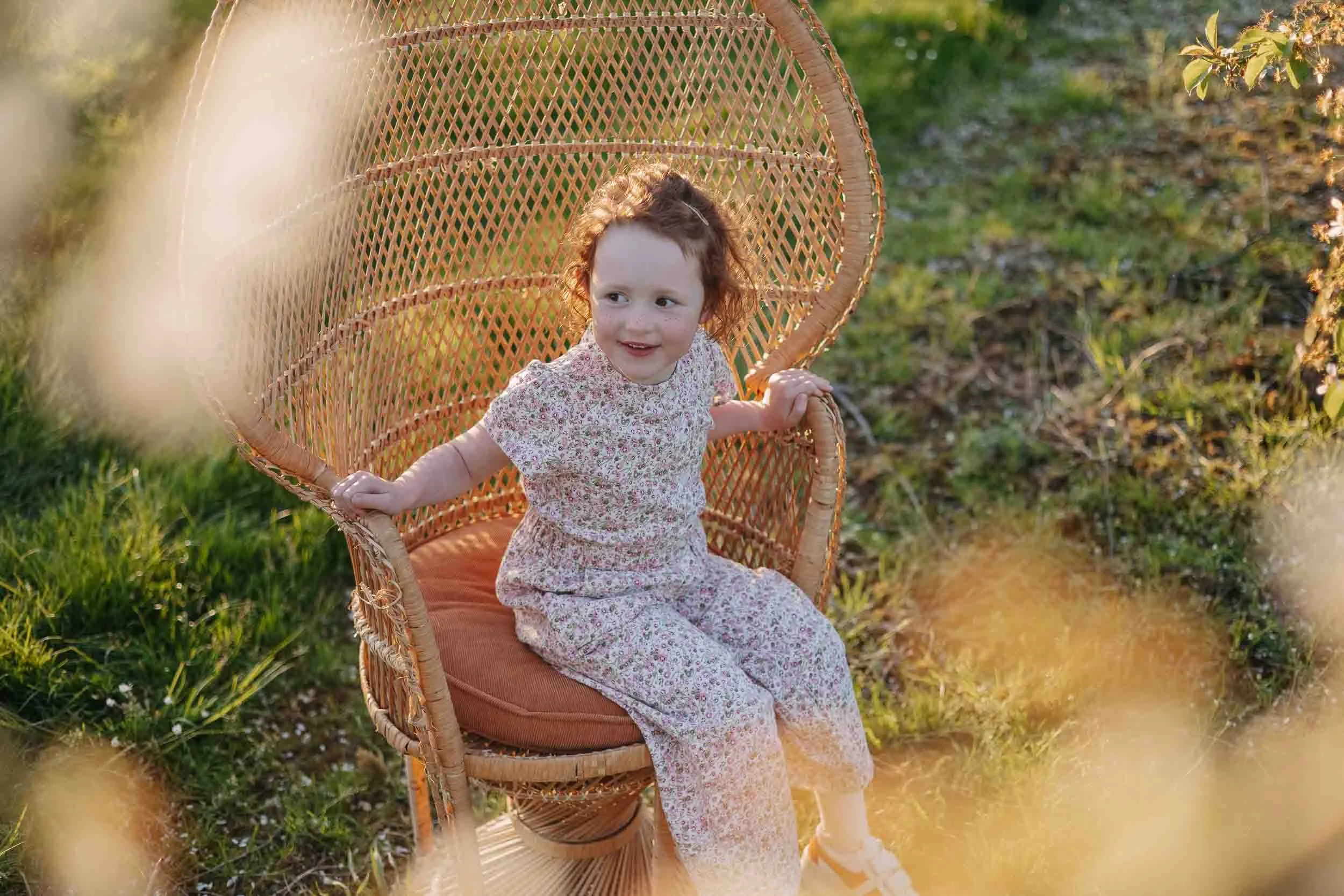 Meisje in een stoel met op de voorgrond onscherpe bloesems.