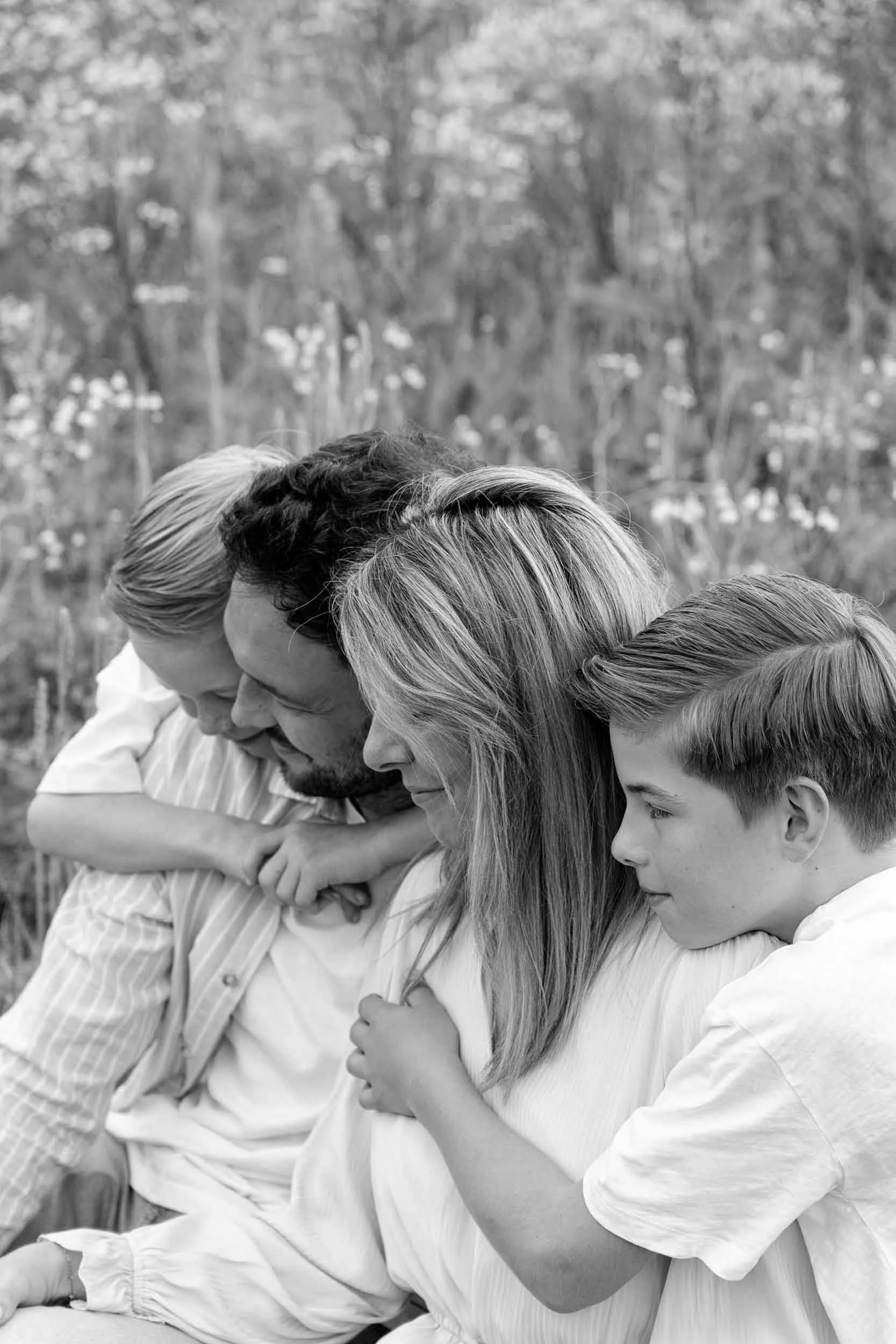 Gezin zitten bij elkaar in het gras, genieten van elkaar met de ogen gesloten