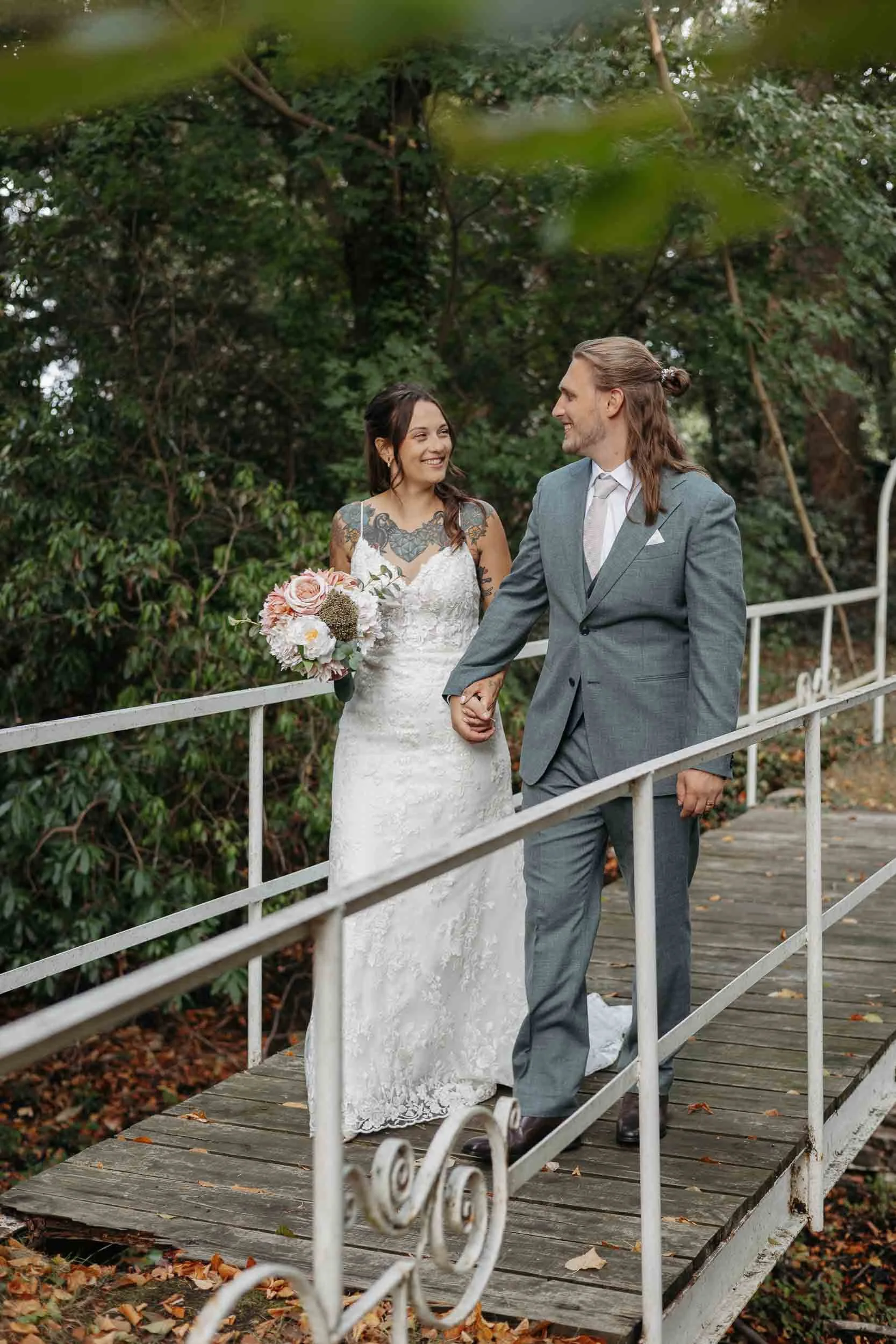 Pas getrouwd koppel dat over een bruggetje wandelt