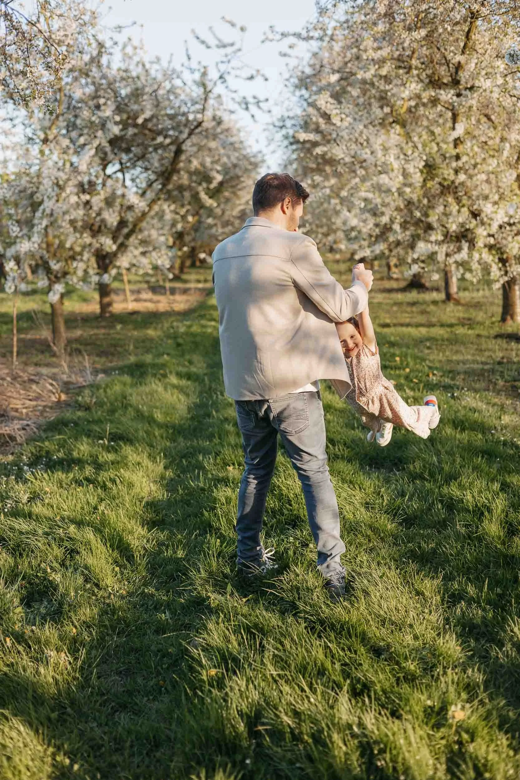 Papa die zijn dochter rondzwaait tussen de bloesems