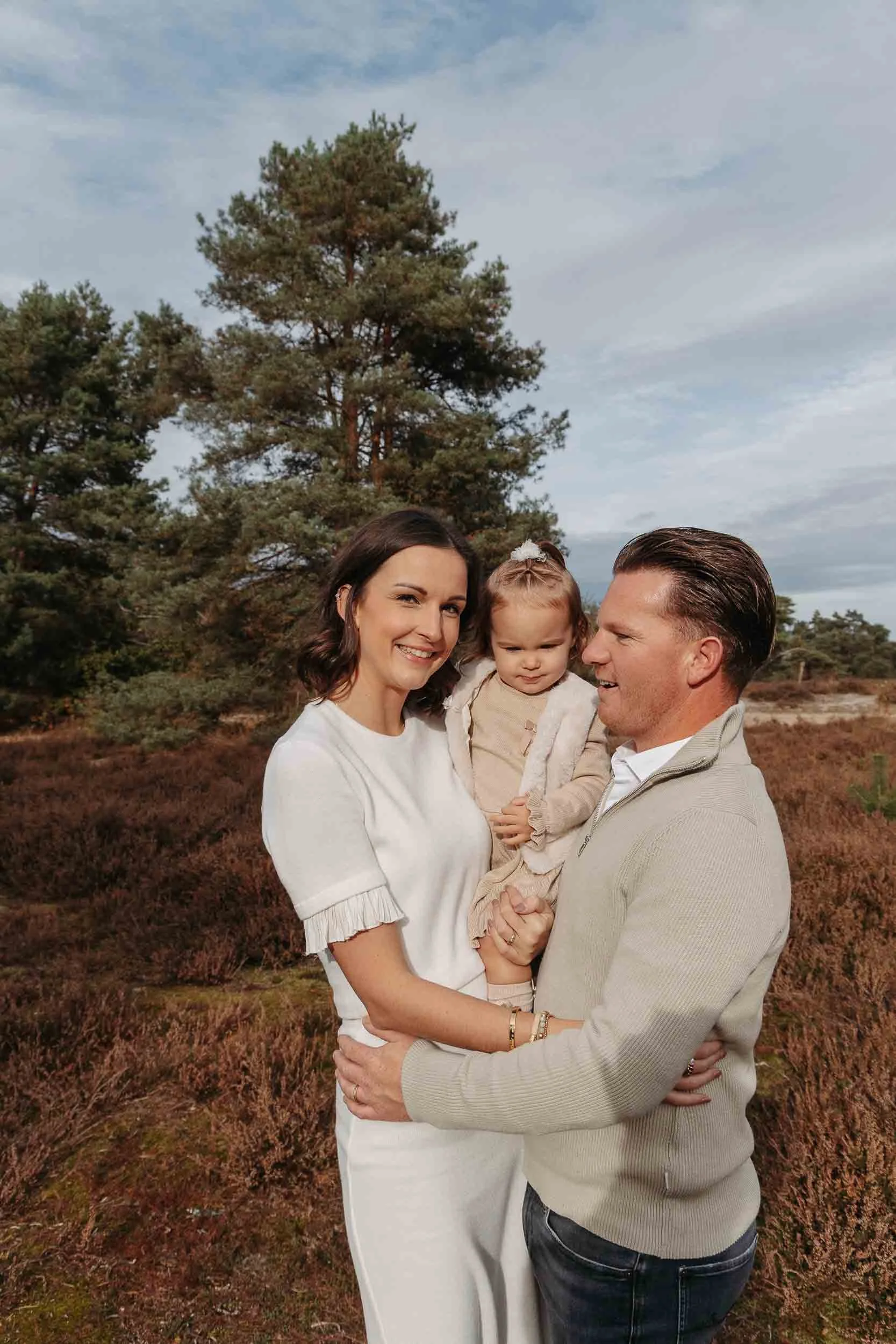 Ouders met hun dochtert tussen hen op een herfstdag op de heide.