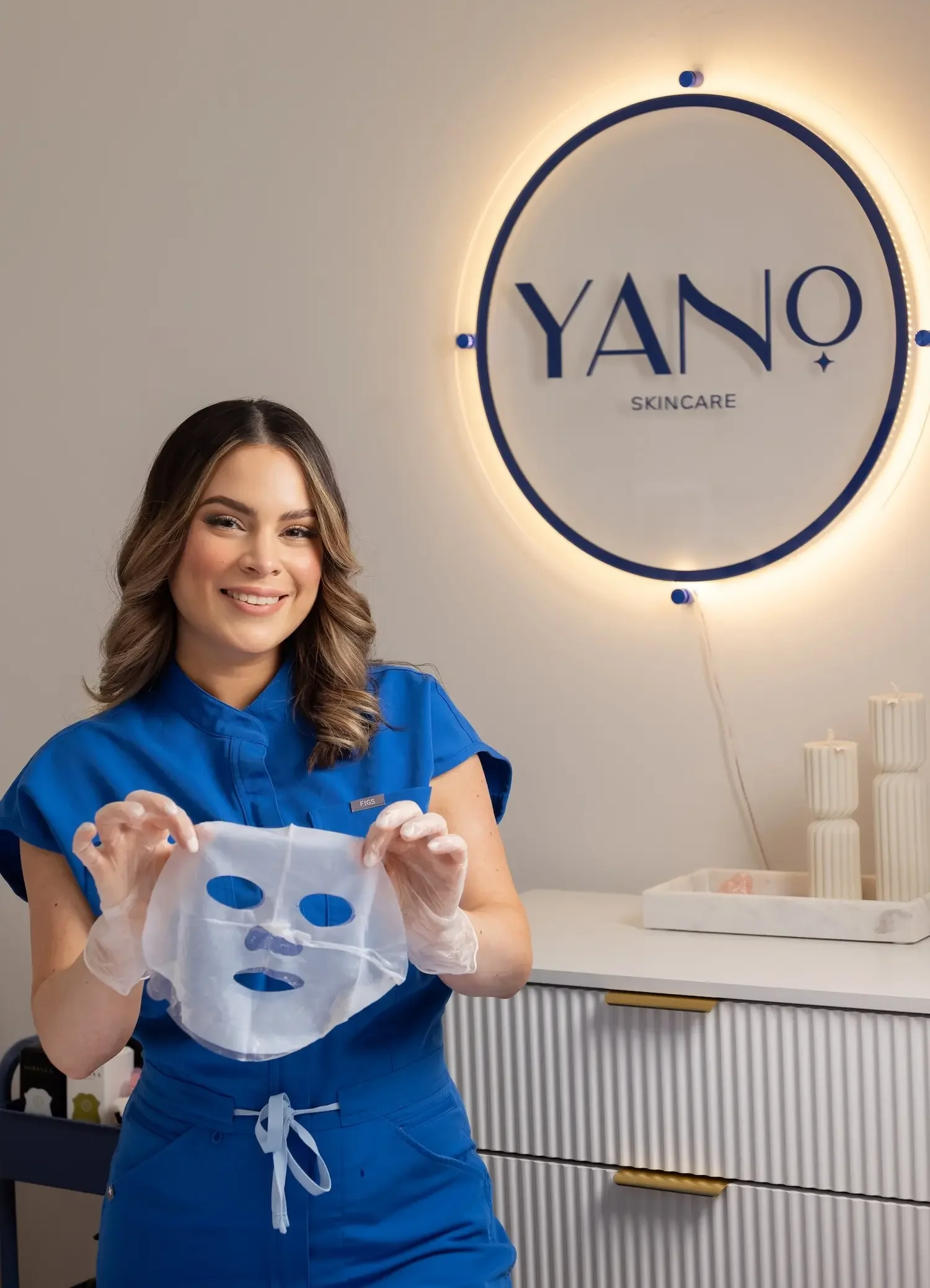 Esthetician displaying a hydrating sheet mask ready for application during a facial.