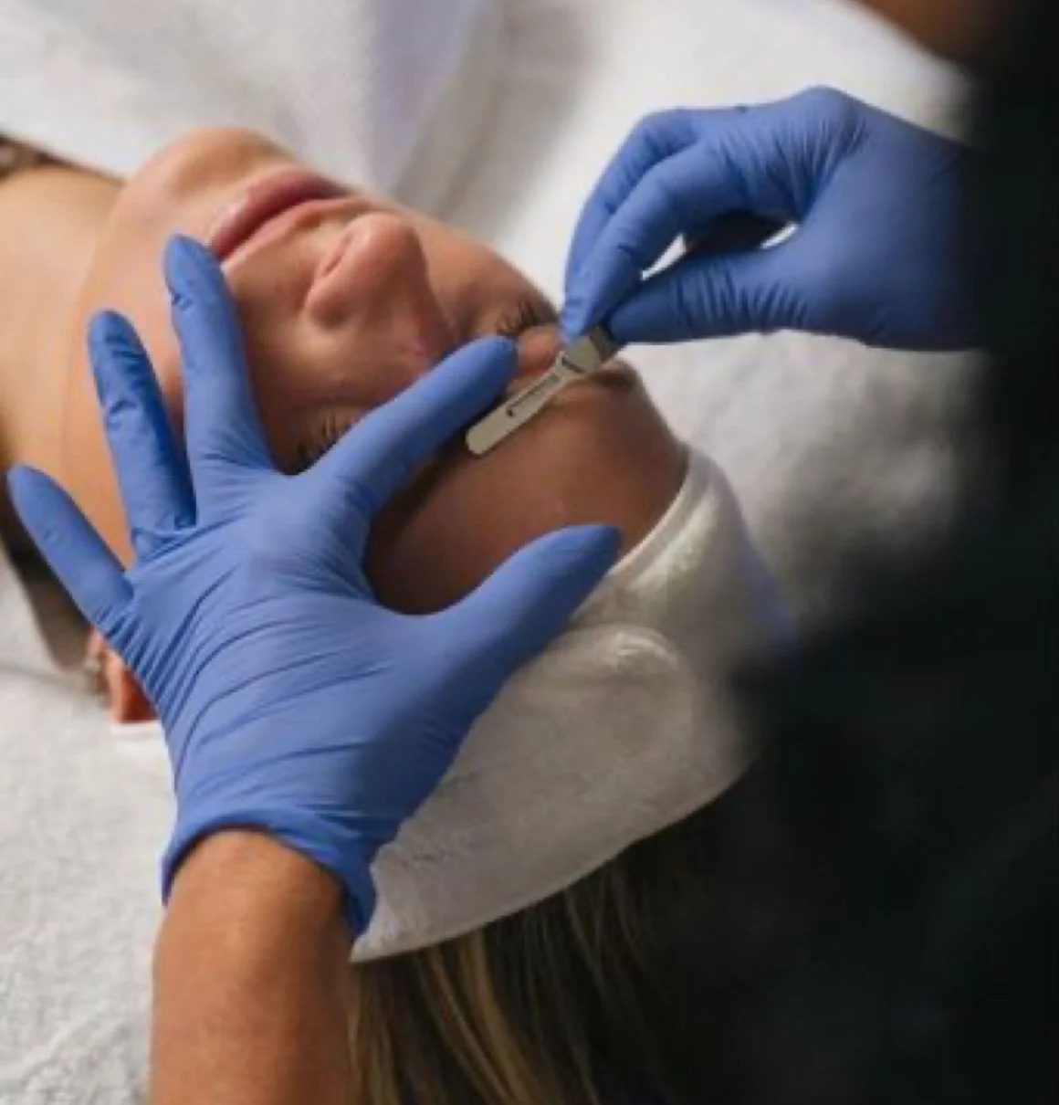 Healthcare professional in blue gloves administering a nasal swab test to a woman lying down.