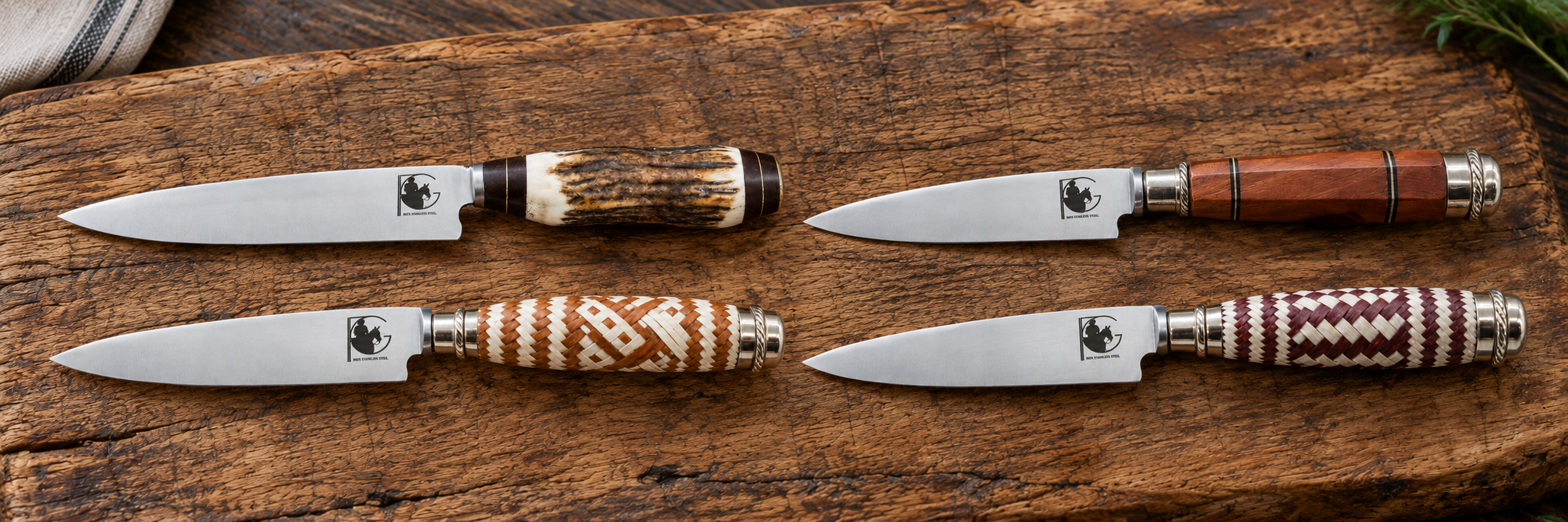 Four Parrilla Gaucha knives with antler, wood and braided leather handles arranged on a rustic wooden board.