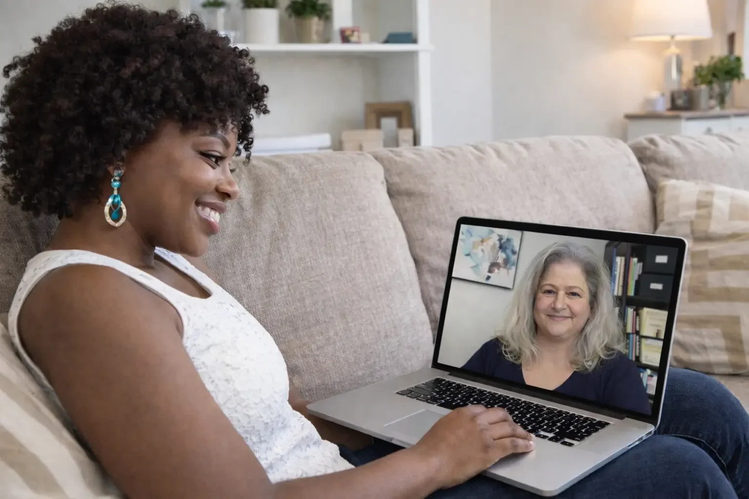 A smiling professional Black woman attends therapy online in Florida from the comfort of her couch at home.