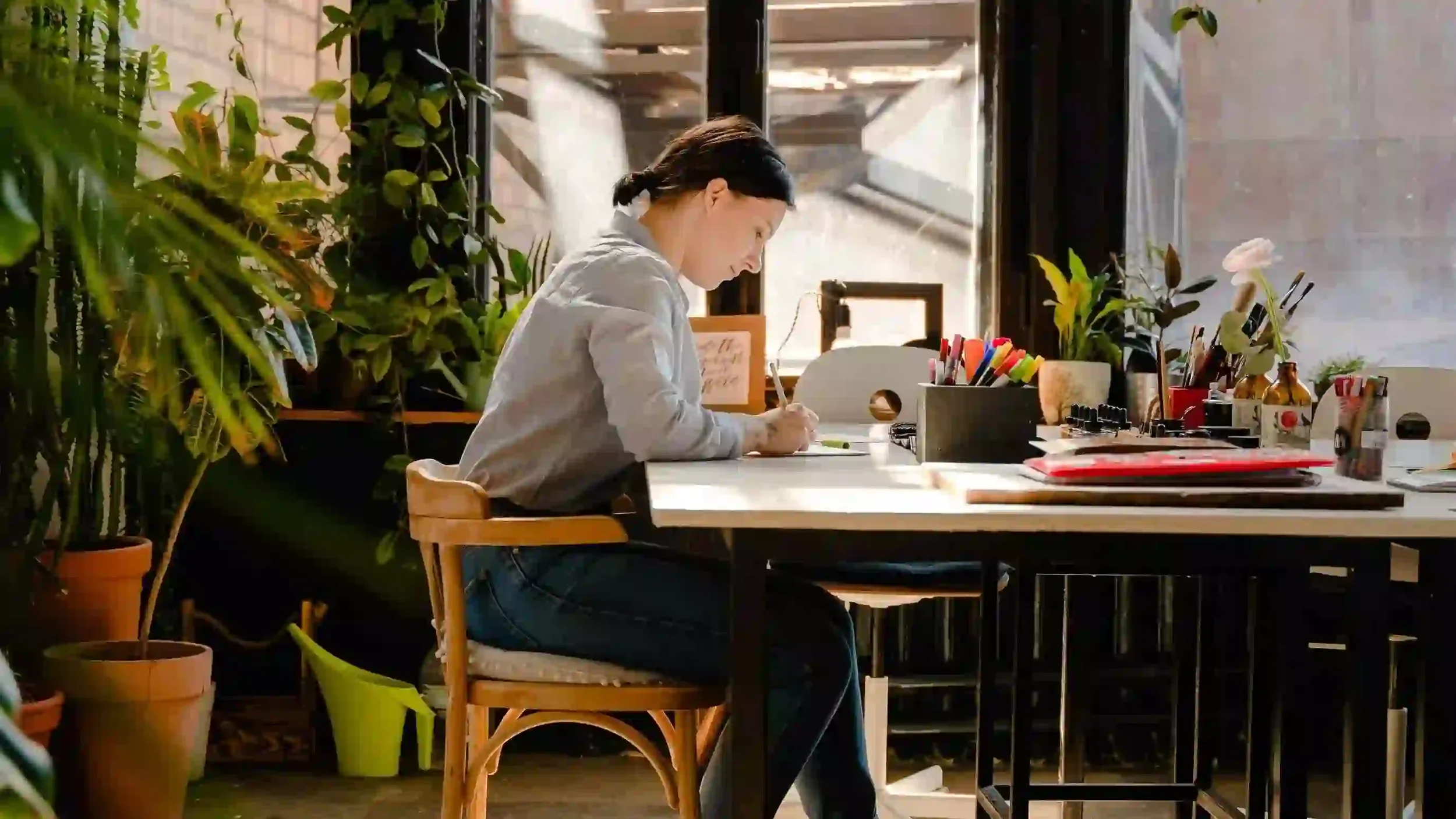 A professional woman sits at a table with study materials while she works on personal growth exercises from therapy.