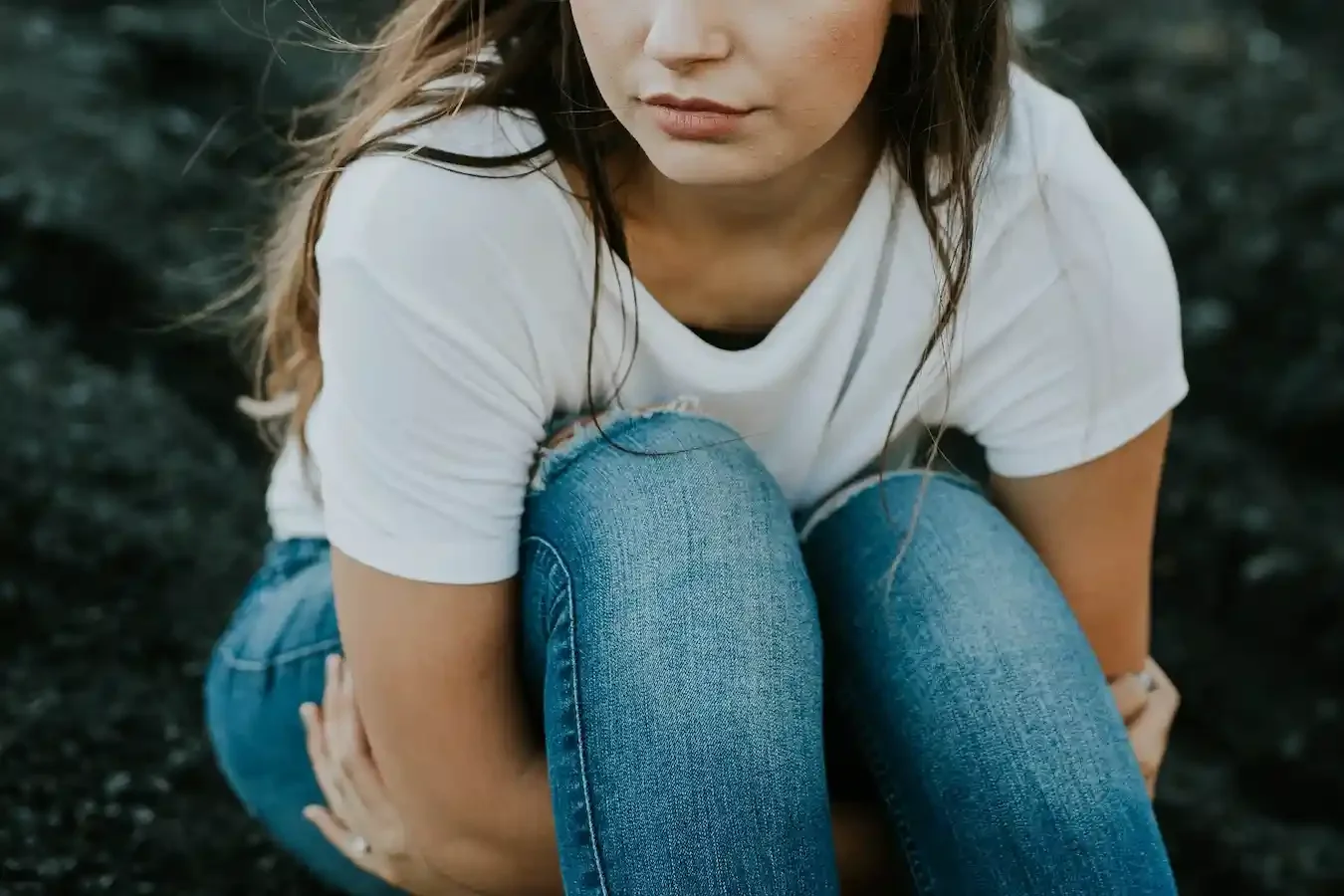 A young woman hugs her knees while thinking about getting help for anxiety through online therapy in Florida.
