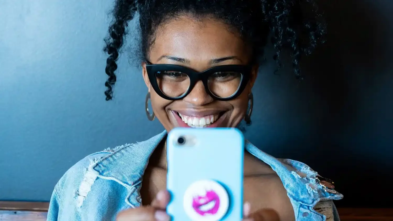 A young college student holding phone in front of her with a big smile on her face