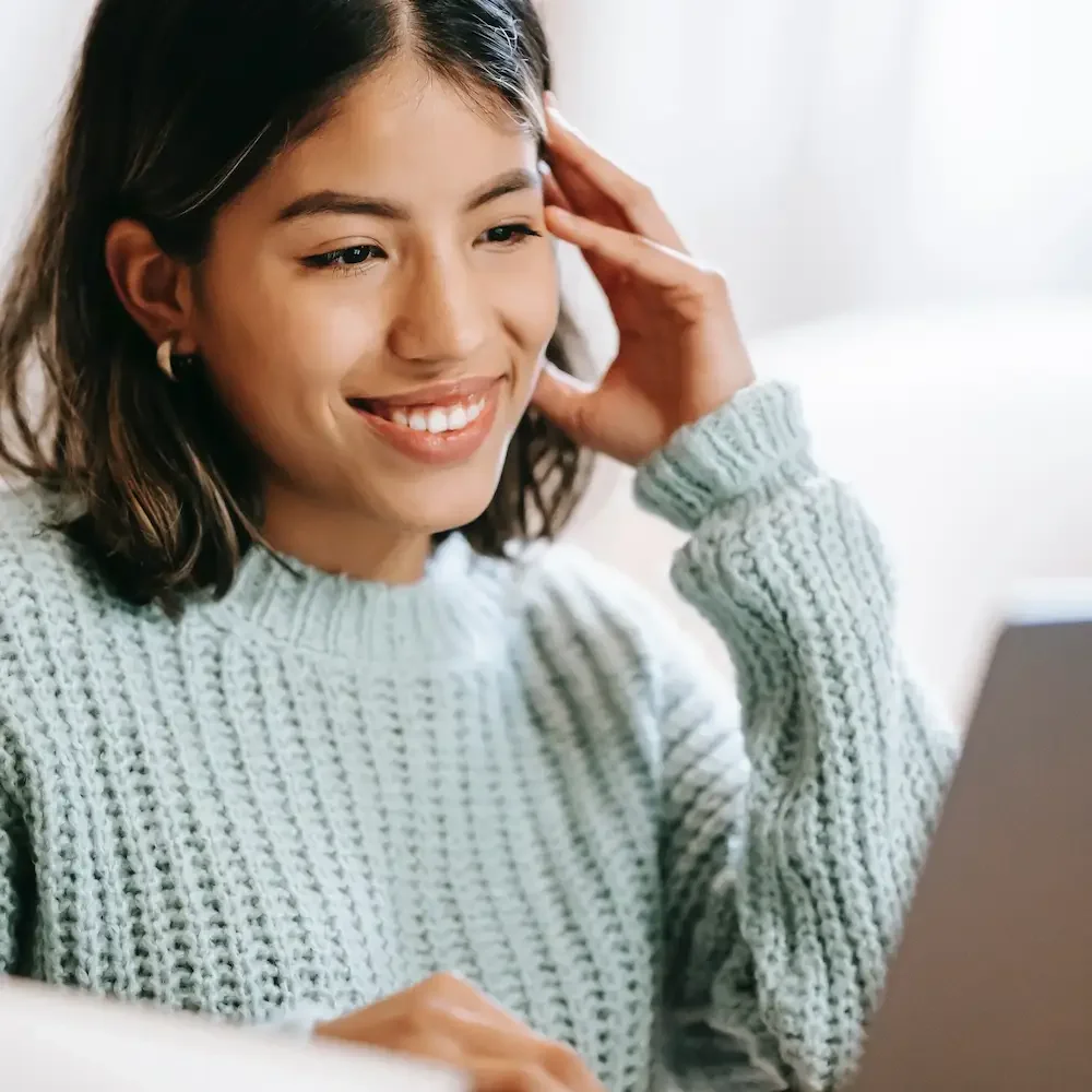 A young professional woman smiles while attending online therapy for addiction recovery in Greenacres, Florida.