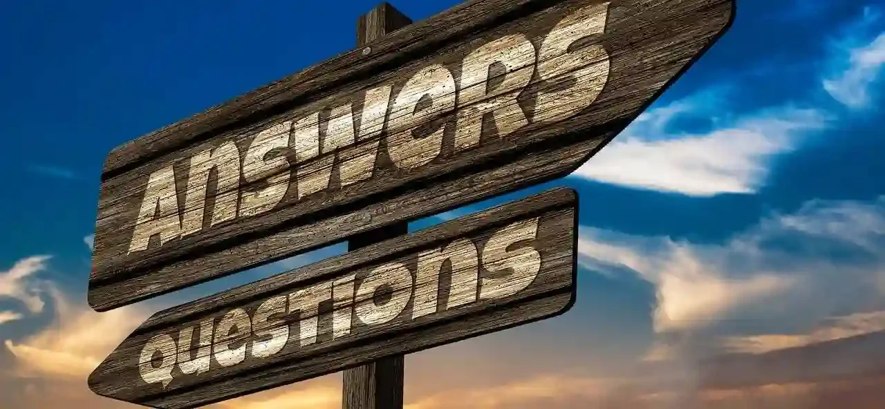 Wooden sign shaped like two arrows say questions and answers and point in opposite directions..