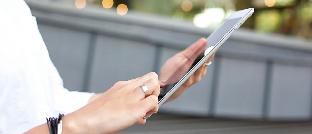 a person's hand scrolling on a tablet to get in touch with their therapist while on the go