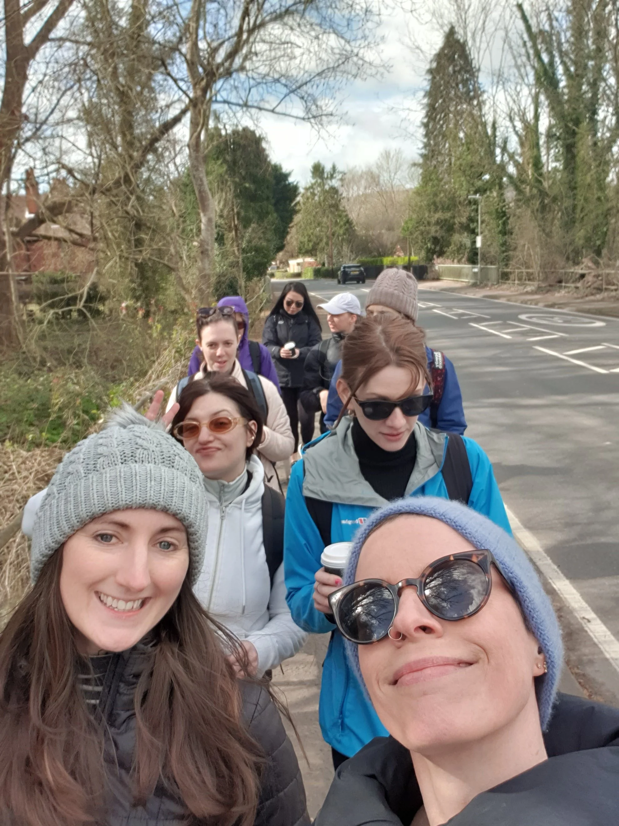 Group of women taking a selfie on a sidewalk during a cloudy day.