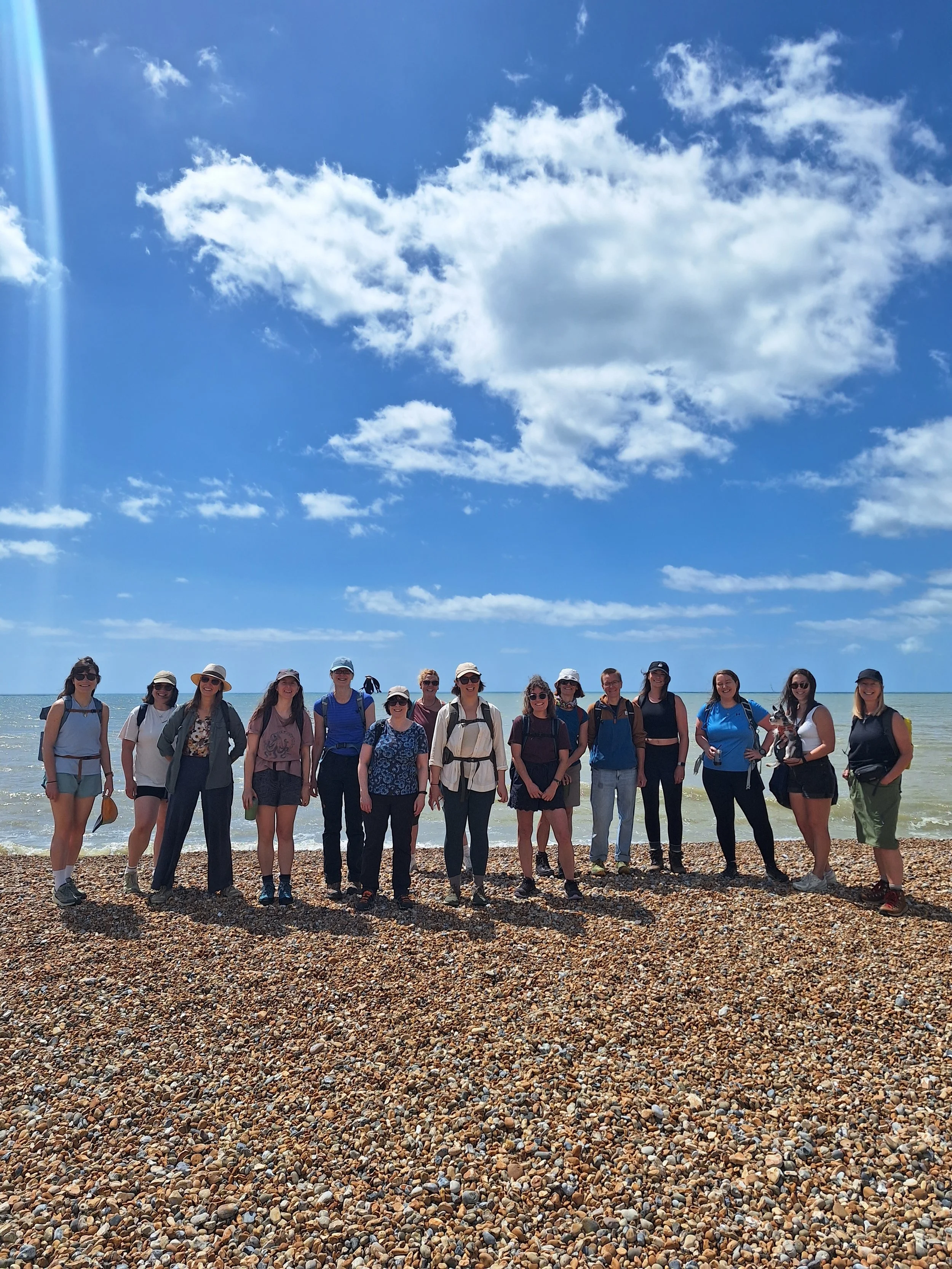 Group of women standing on a pebble beach with the ocean and sky in the background