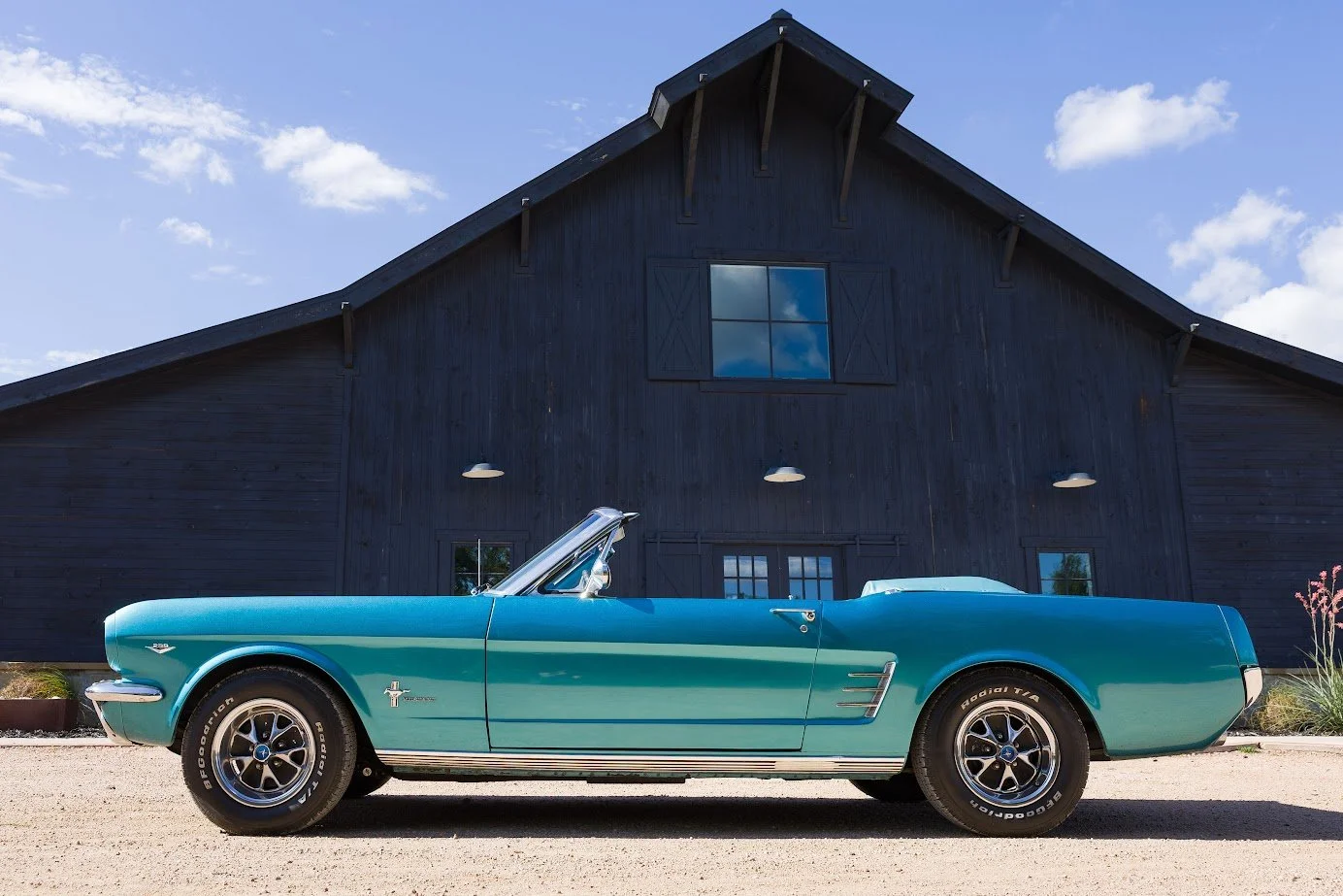 Blue 1966 Mustang convertible in front of the ATX Classic Cars barn, chauffeur-driven rental in Dripping Springs TX