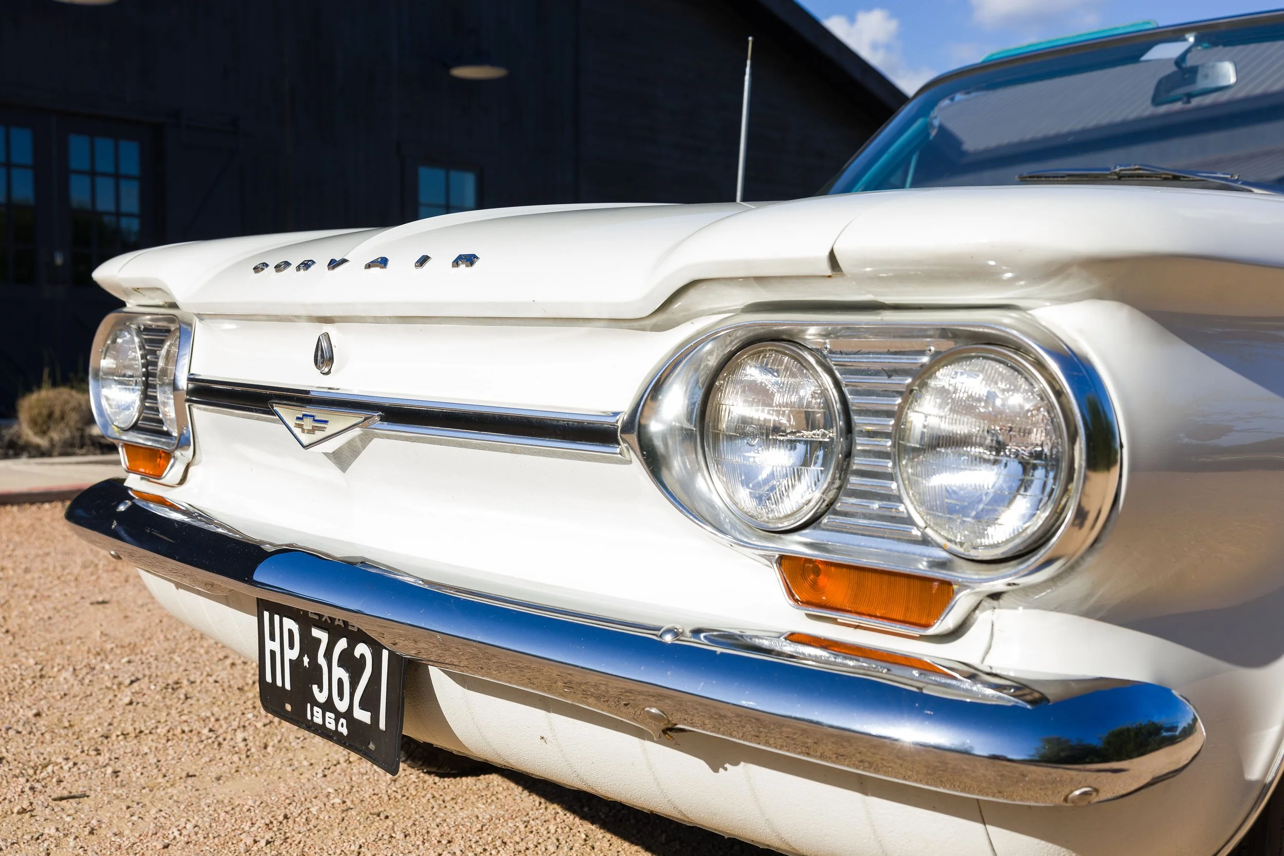 Front corner of a white 1964 Chevy Corvair convertible showing the chrome headlights and bumper