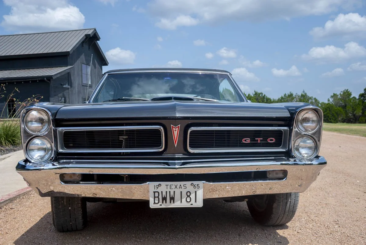 Front view of Poncho, a charcoal 1965 Pontiac GTO convertible with the GTO grille badge