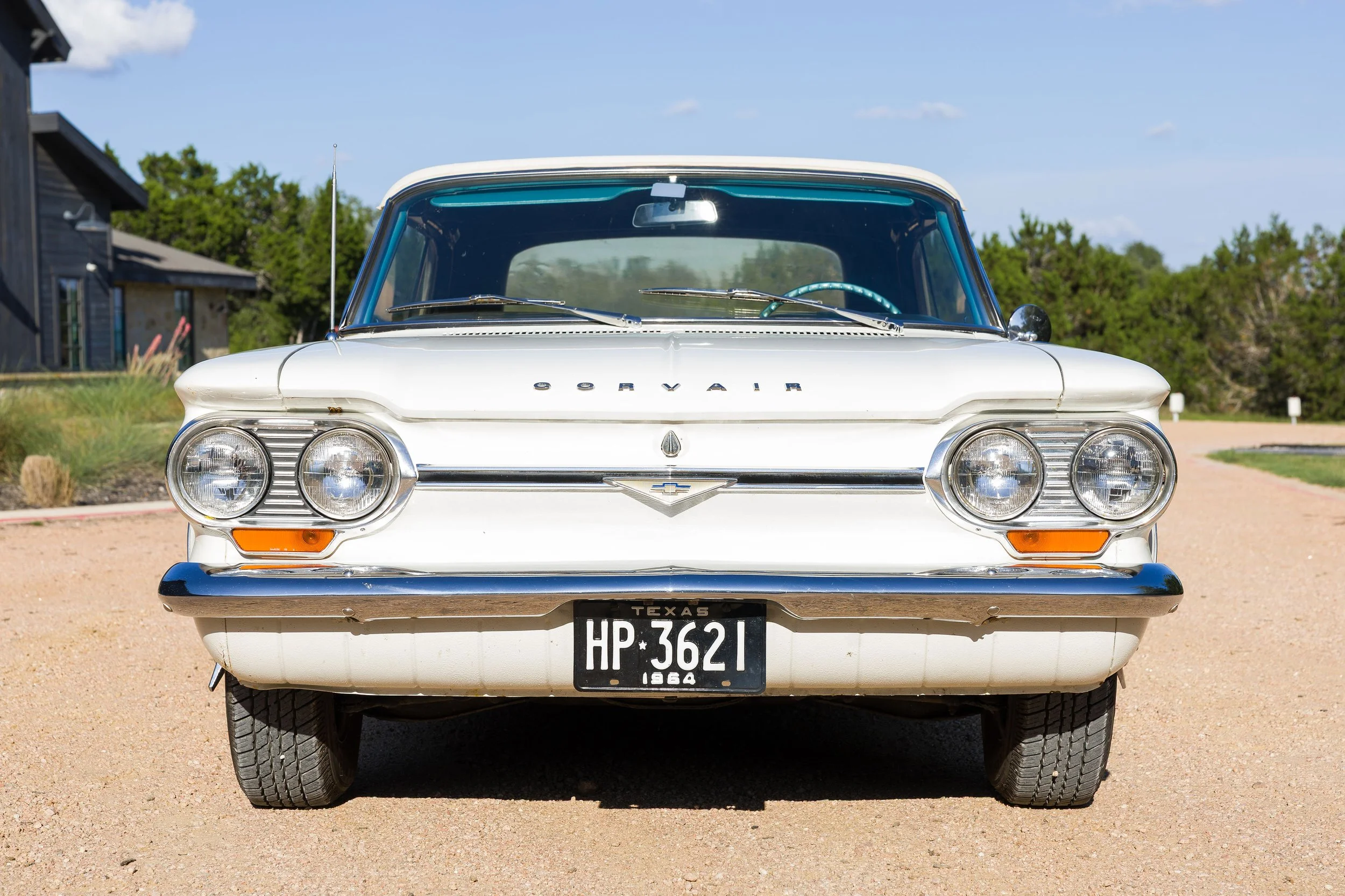 Front view of Ralphie, a white 1964 Chevy Corvair convertible with chrome headlights