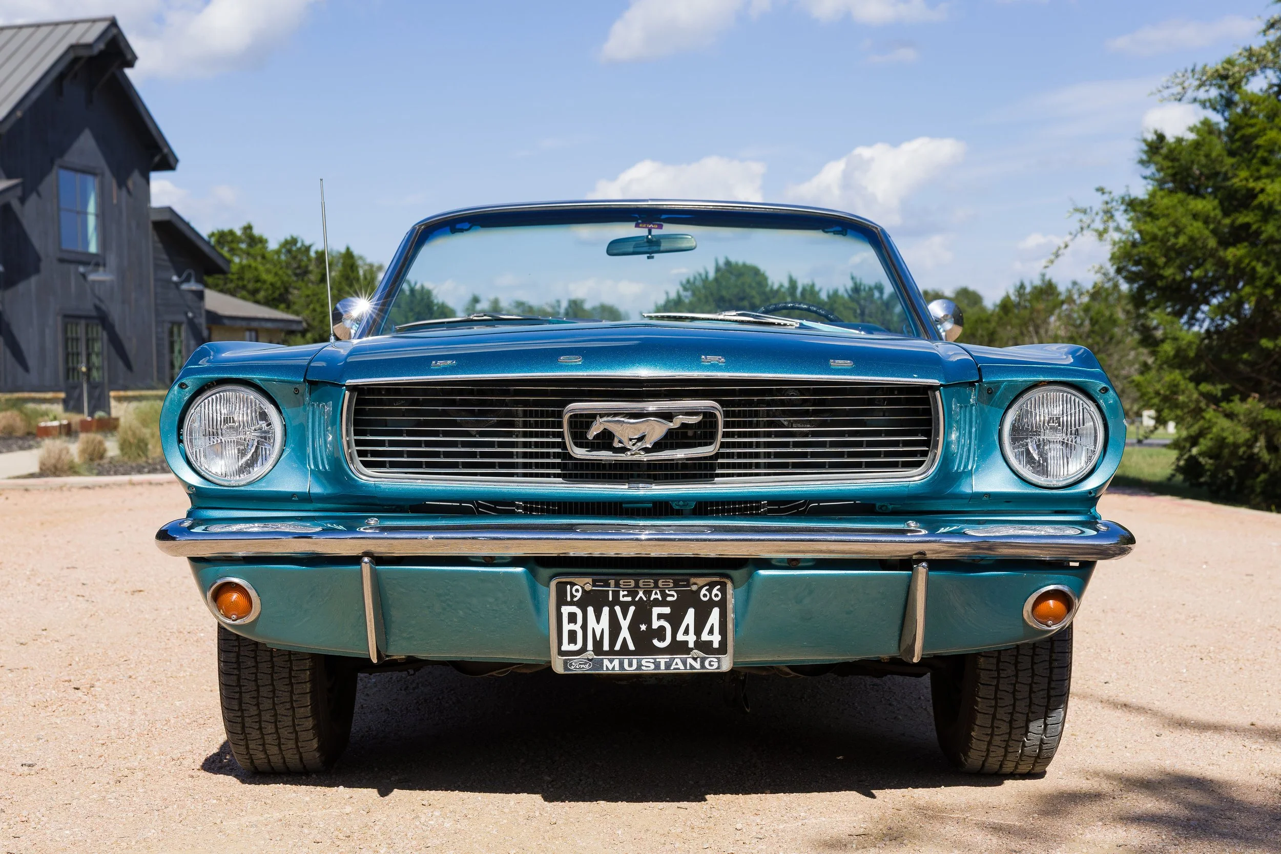 Front view of a blue 1966 Ford Mustang convertible with the pony emblem on the grille