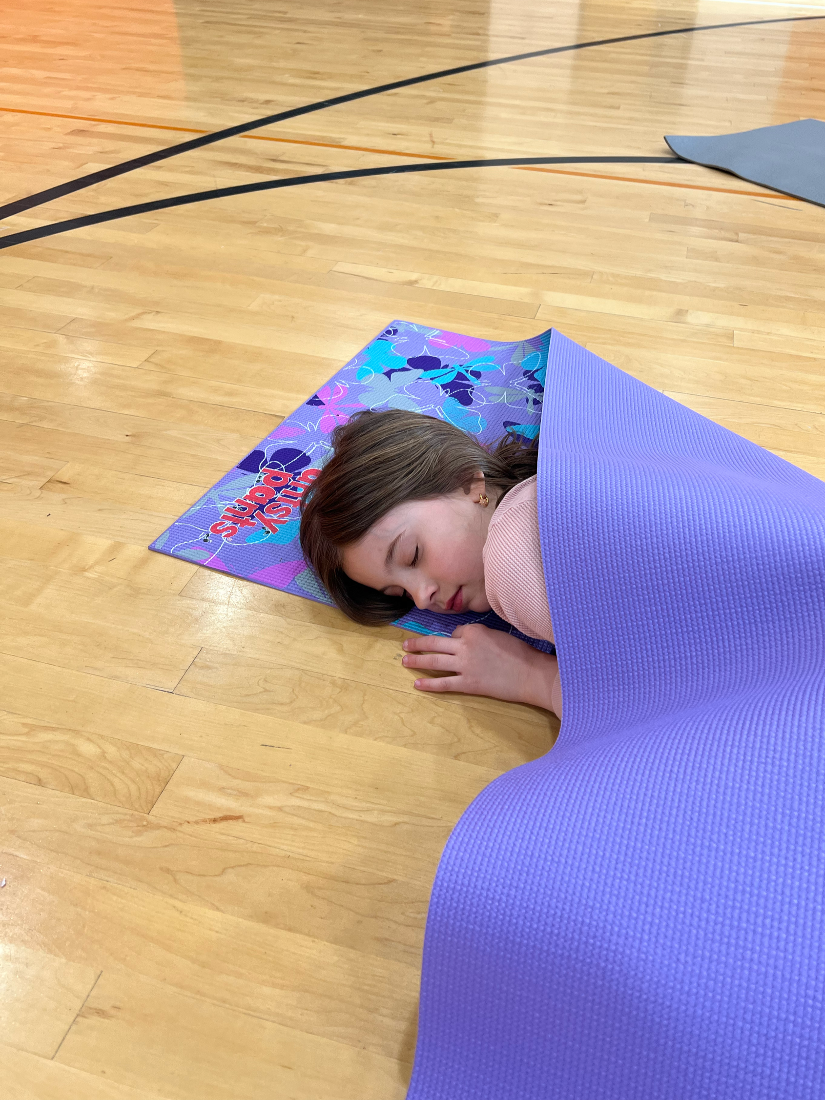 Child resting and calming body during mindfulness activity in Roseville kids yoga and wellness program