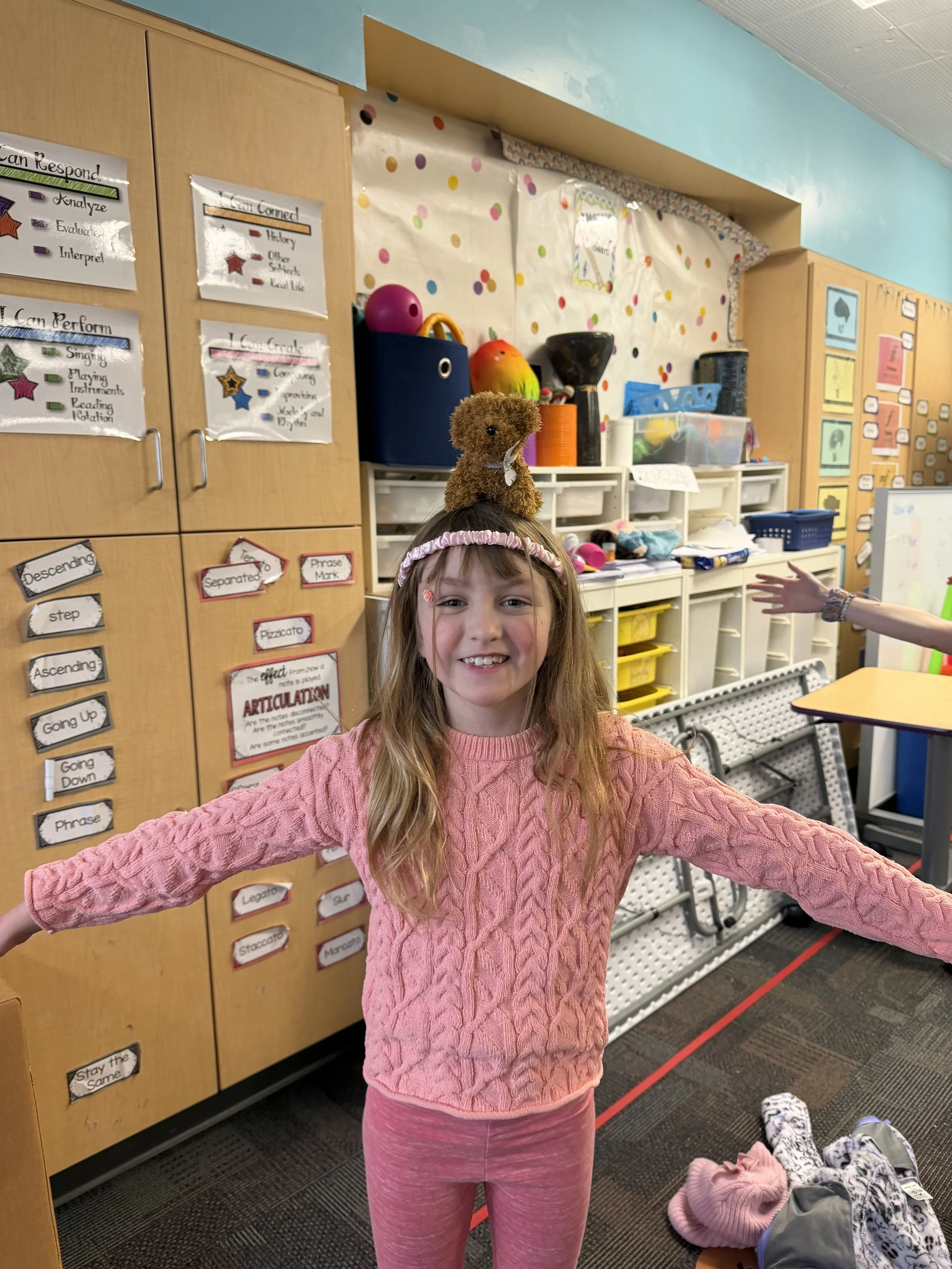 Child balancing a stuffed puppy during a playful puppy-themed kids yoga activity at a Pose & Play™ retreat in Minnesota.