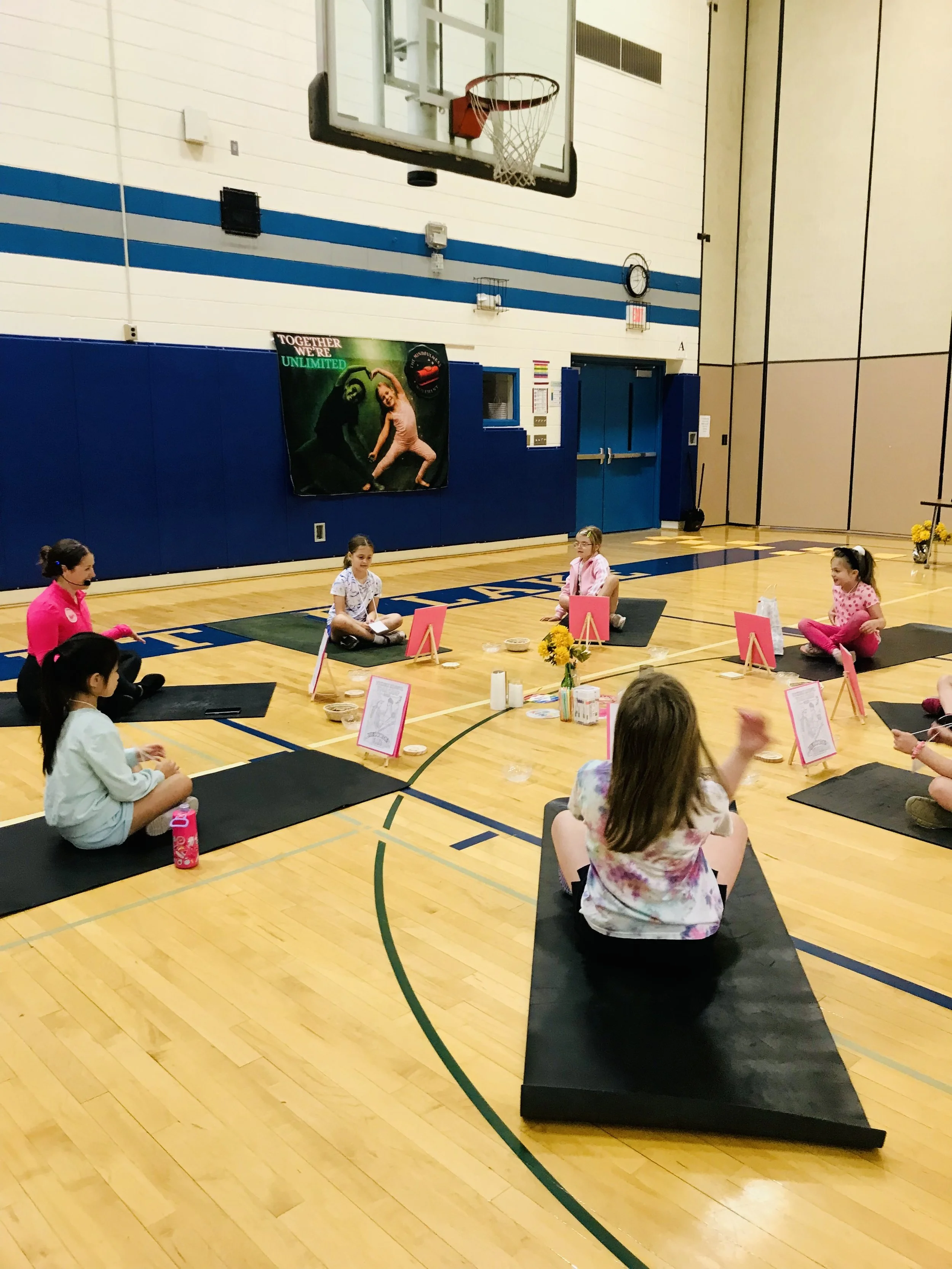 Children sitting in a circle practicing mindfulness and yoga during a kids camp in Mounds View Minnesota gym setting