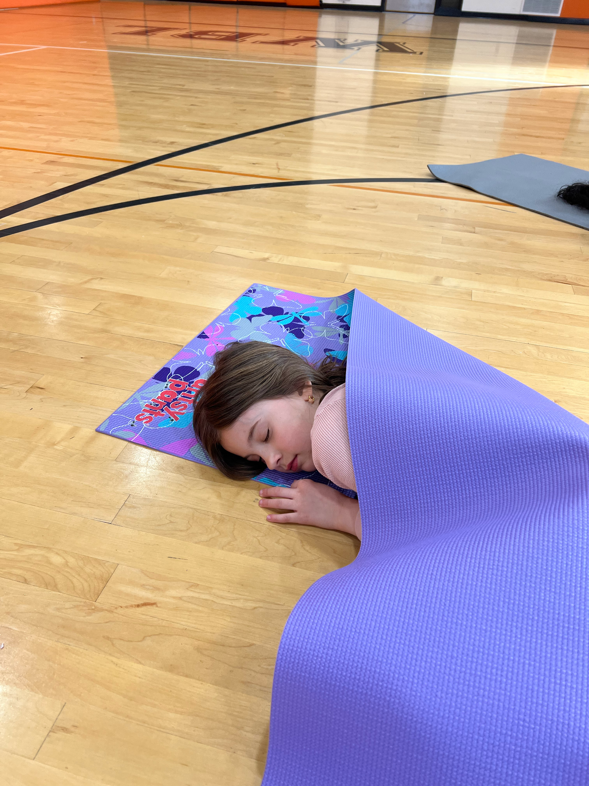 Child resting in shavasana during a calming kids mindfulness and yoga class in White Bear Lake MN