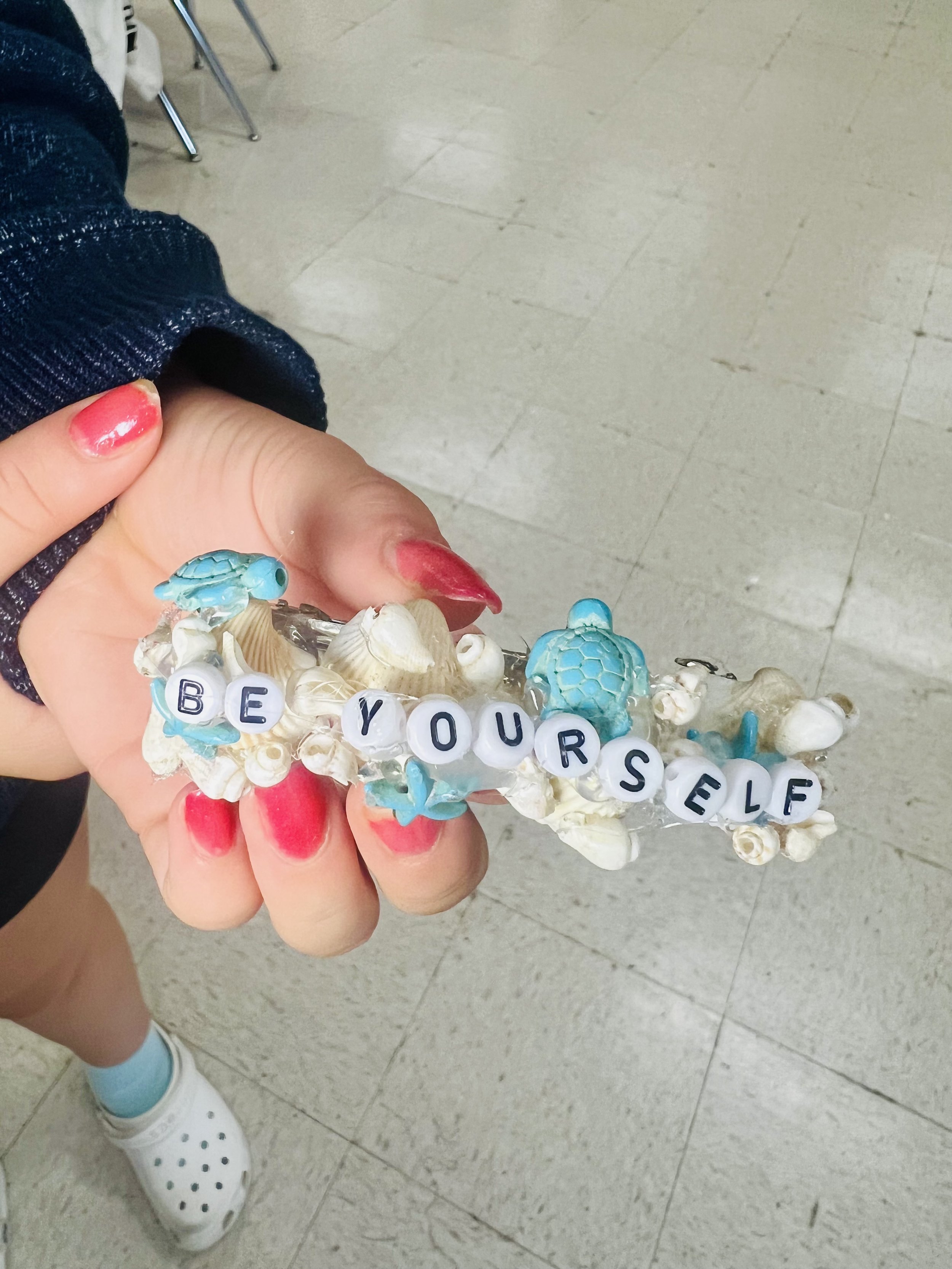Middle school student holding a positive affirmation hair clip craft from Make and Take Calming Creations after-school program in Mounds View MN