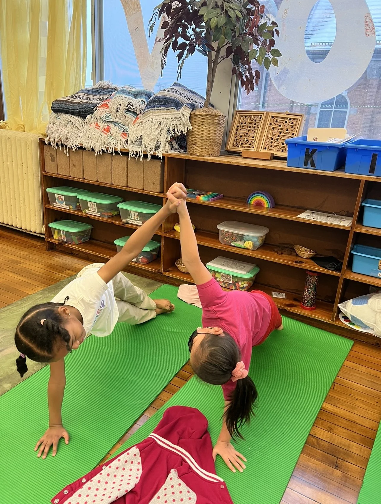 Two children practicing a side plank partner yoga pose during after school kids yoga in Roseville MN