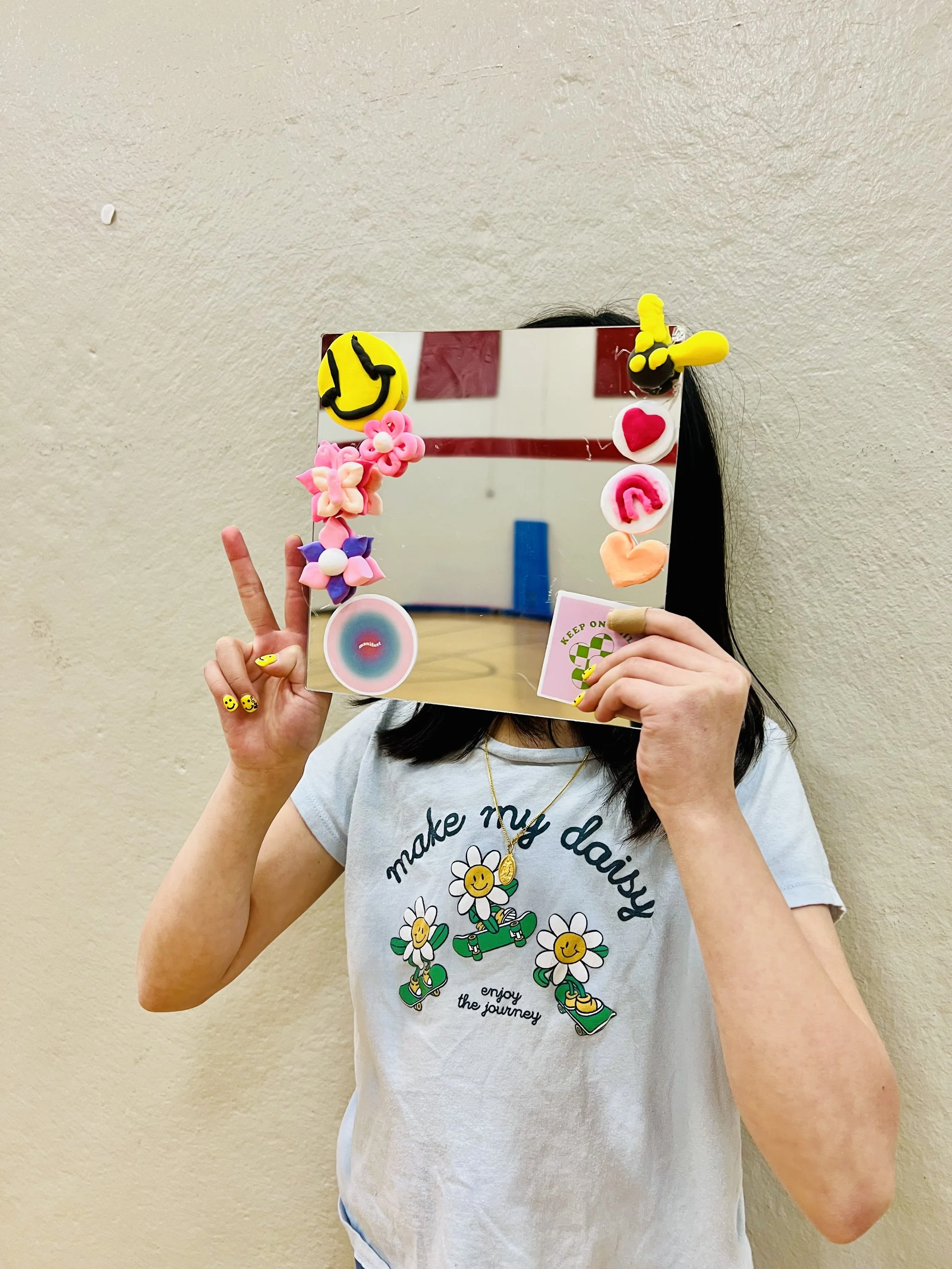 Child holding a DIY affirmation mirror craft during a Roseville Community Education summer camp focused on mindfulness and confidence building.