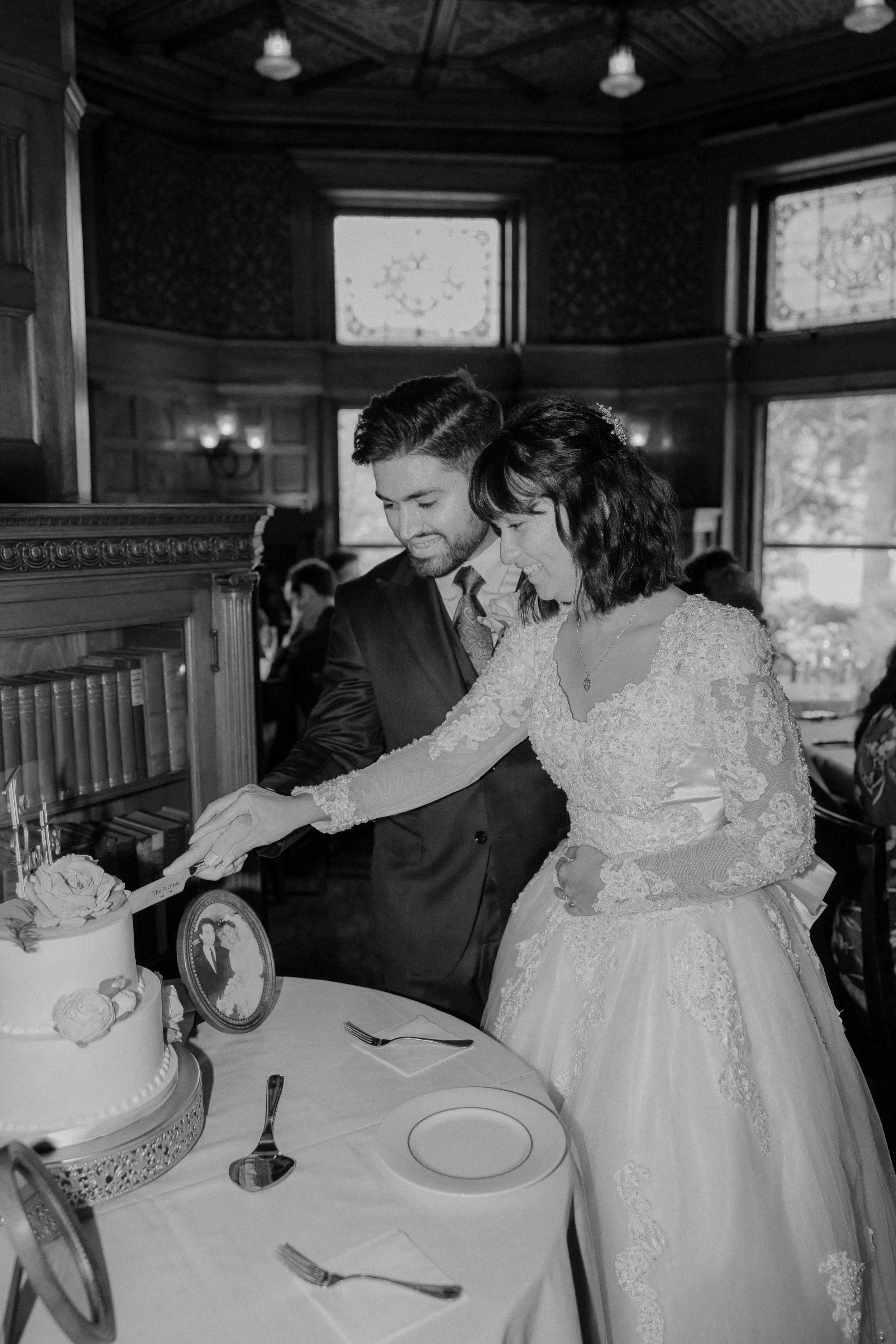 A bride and groom cutting a wedding cake together in a decorated, vintage-style restaurant.