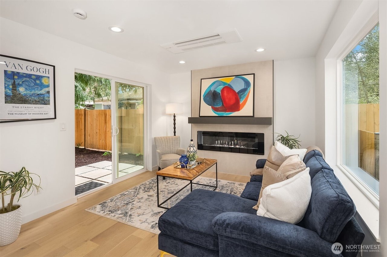 Modern living room with blue sofa, abstract painting, glass door, and indoor plants.