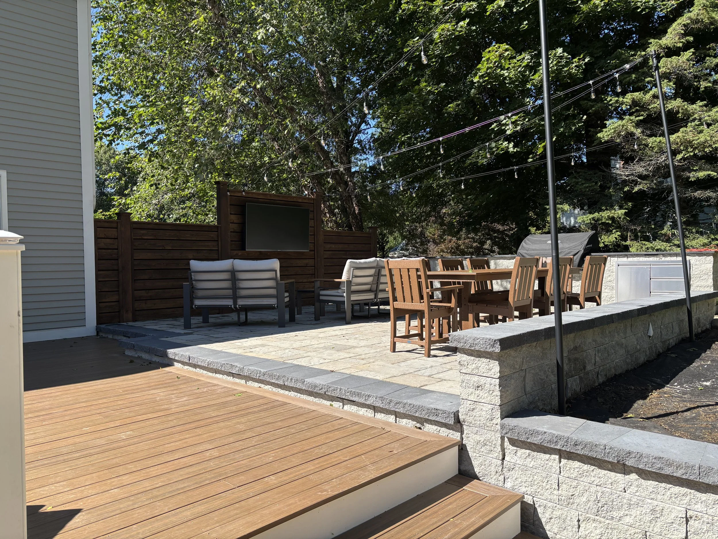 Cozy chairs surround the outdoor TV and a dining table provides plenty of room for entertaining on summer nights