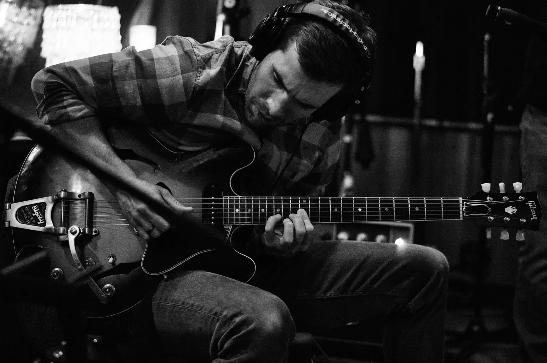 A session musician playing electric guitar while wearing headphones