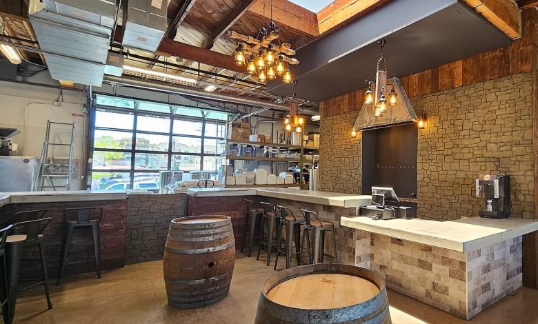 Modern bar interior with brick walls, wooden barrels, a white marble counter, and industrial-style lighting fixtures.