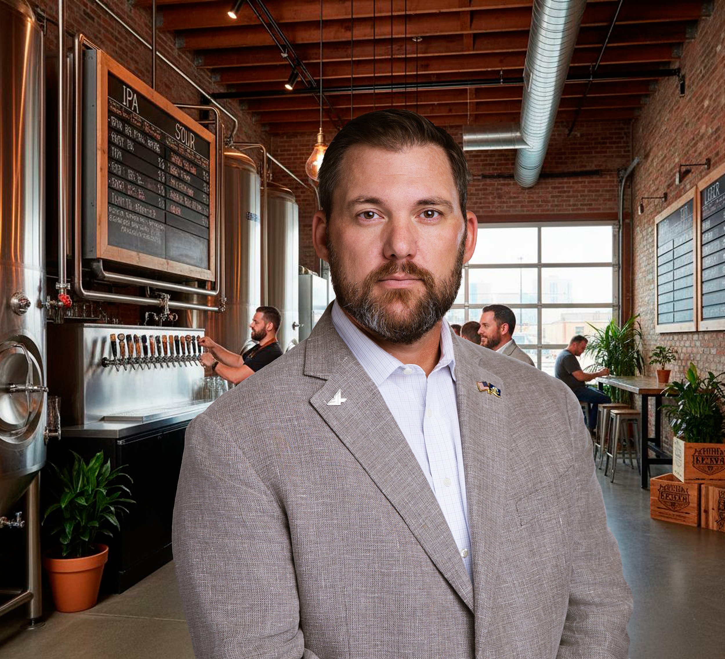 A man in a gray suit with a stomach pin, standing in a brewery or bar with industrial decor, large windows, and beer taps in the background.