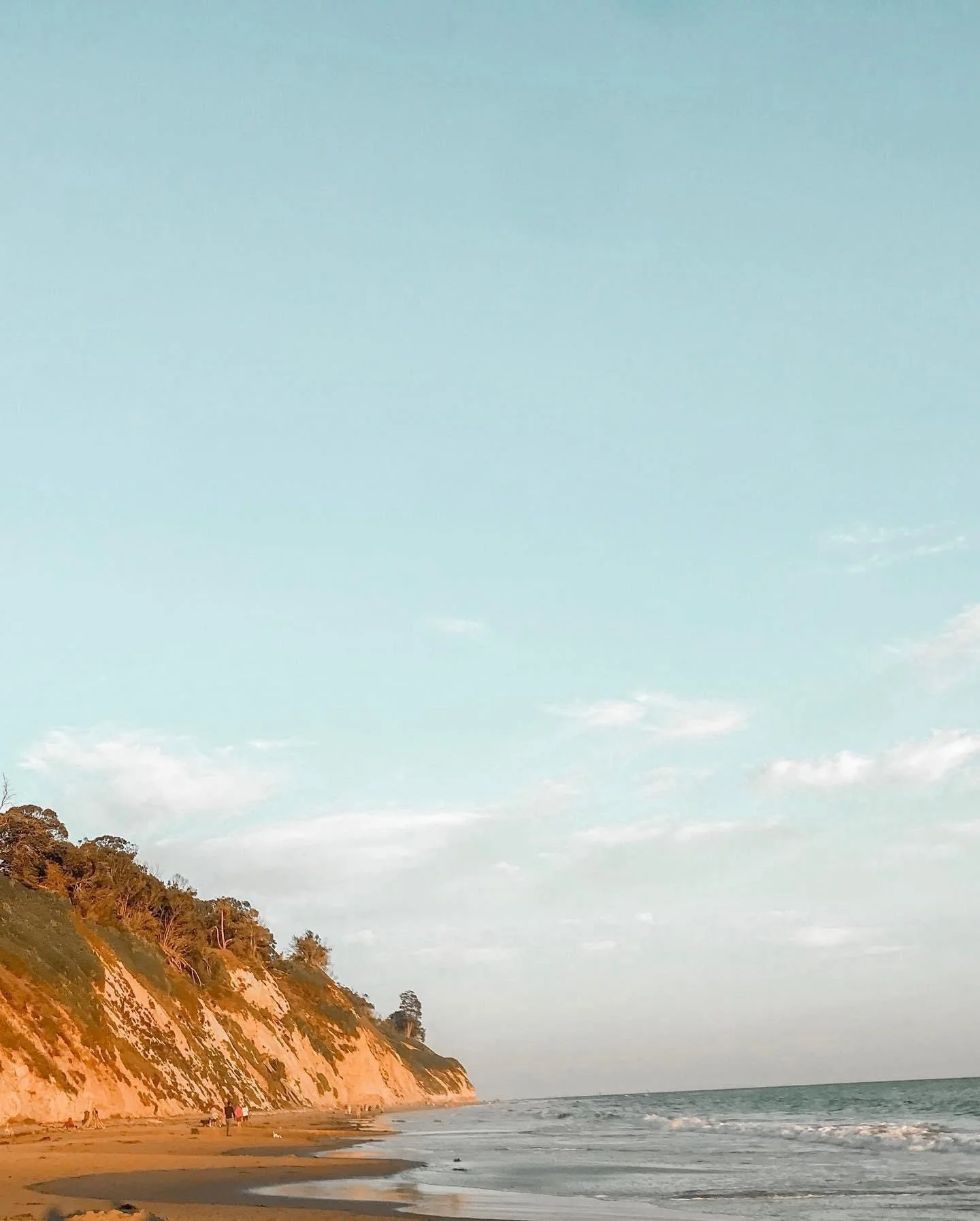 Brown mountain on ocean with blue sky with white clouds