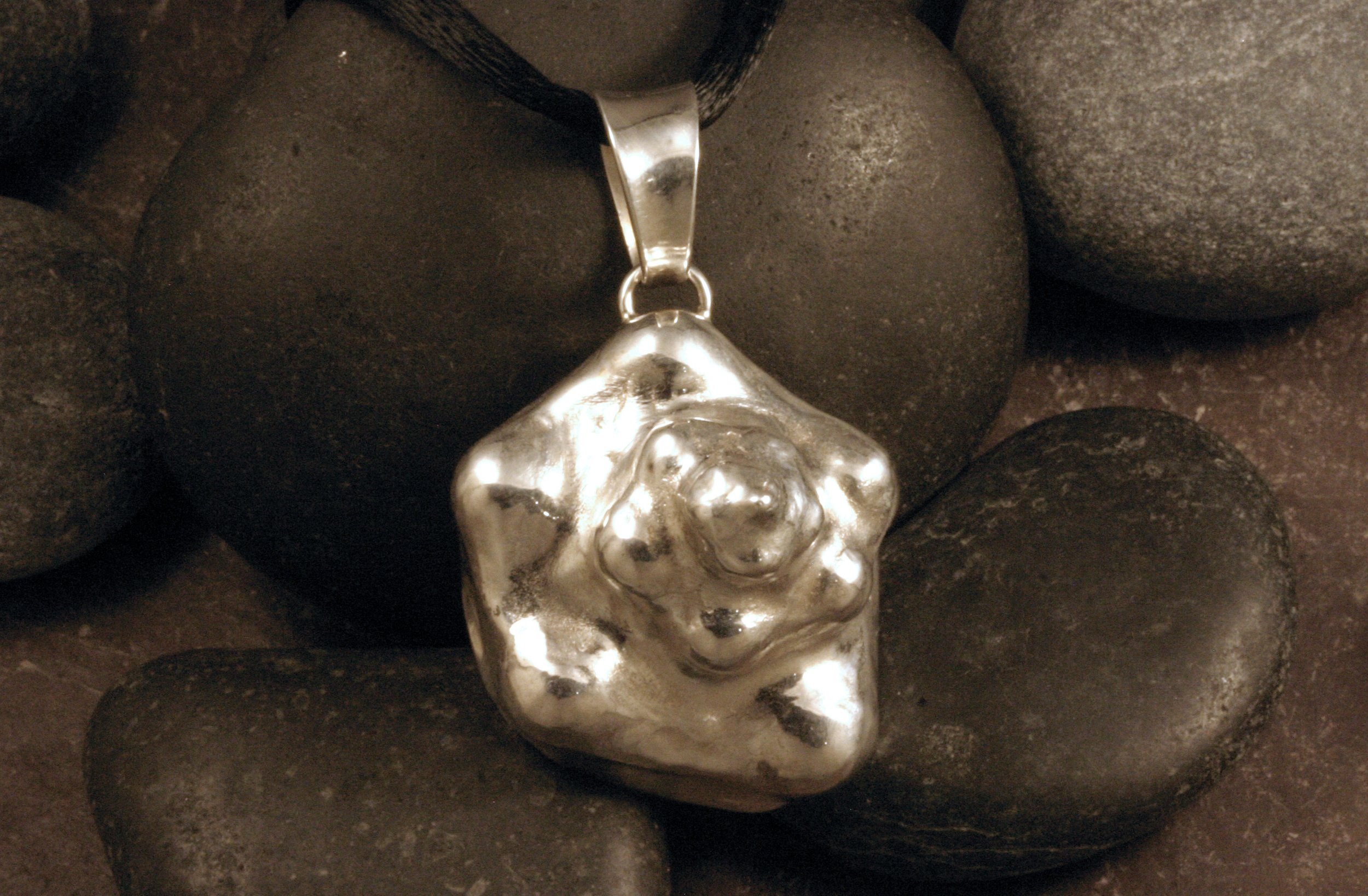 A front view of a large sterling silver conch shell pendant.