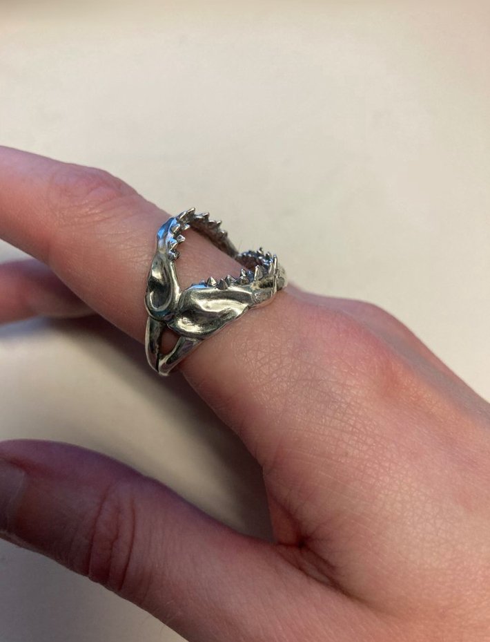 A side view of a sterling silver shark jaw ring on a model's finger.
