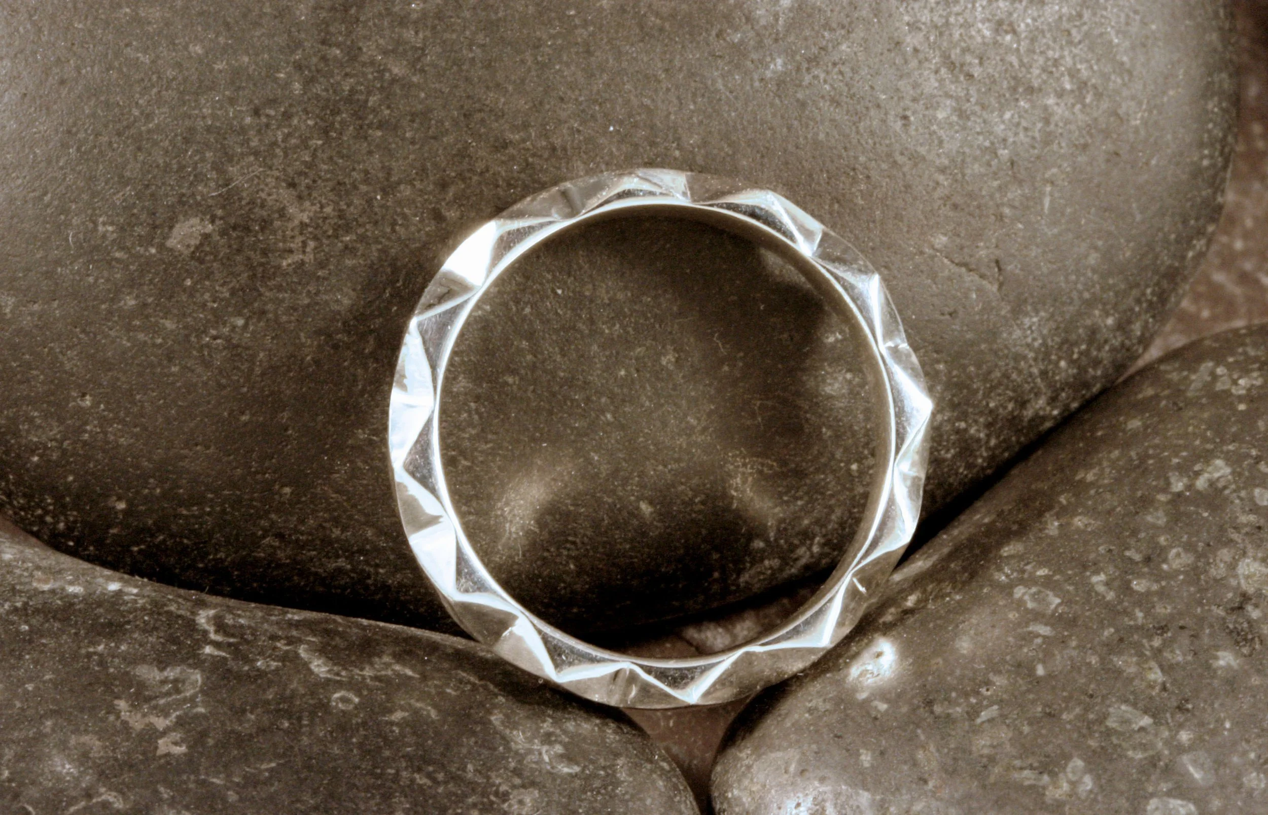 A side view of a modern sterling silver geometric diamond patterned ring.